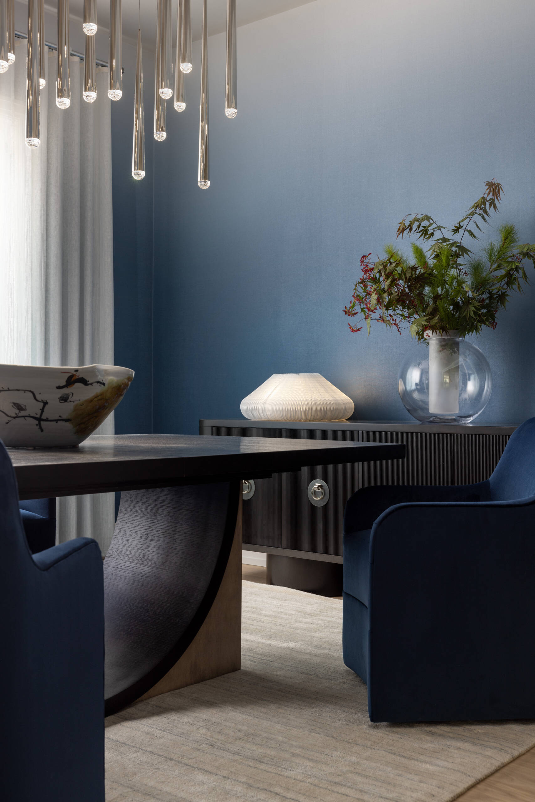 The dining room leans into atmosphere. A wood table, comfortable chairs, and a chandelier with a raindrop shimmer create a soft halo after dark. The walls carry gentle color, just enough to warm the scene without shouting. It is the kind of room that makes every dinner look like a celebration.