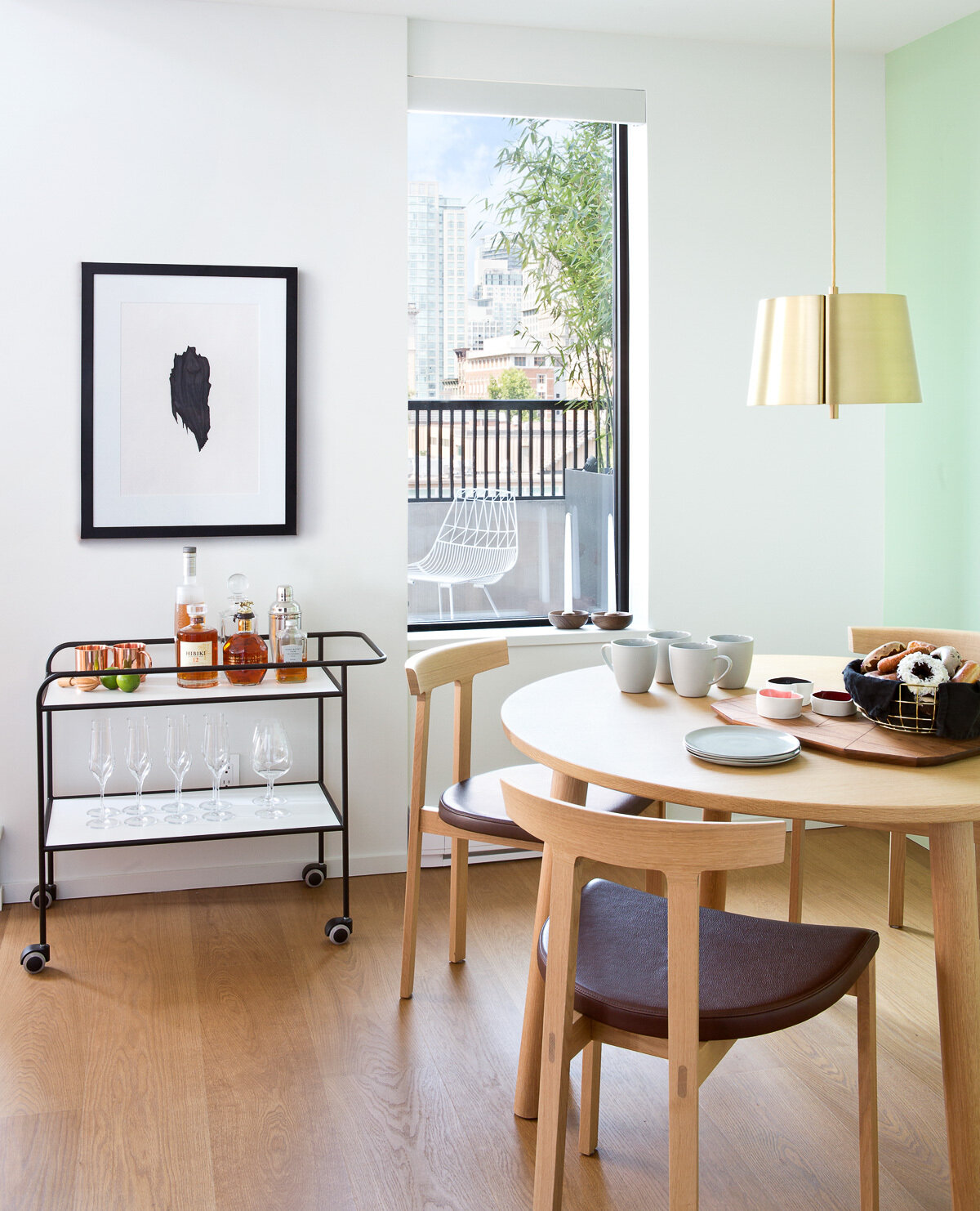 A light green wall in the dining area provides a subtle shift in tone without interrupting the flow of white and wood. It creates just enough variation to define the zone while keeping the palette calm.