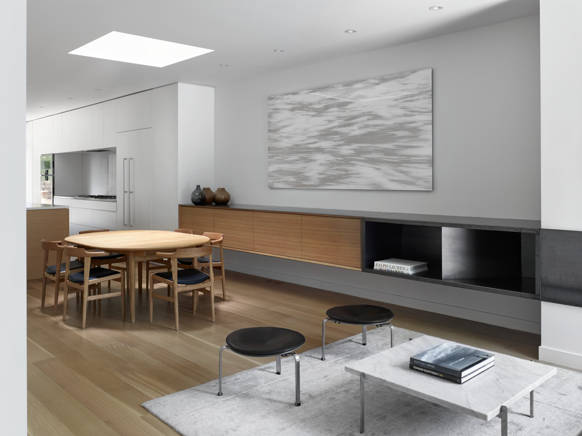 A serene dining space beneath a dramatic skylight that glows at night, blending minimal design with architectural flair.