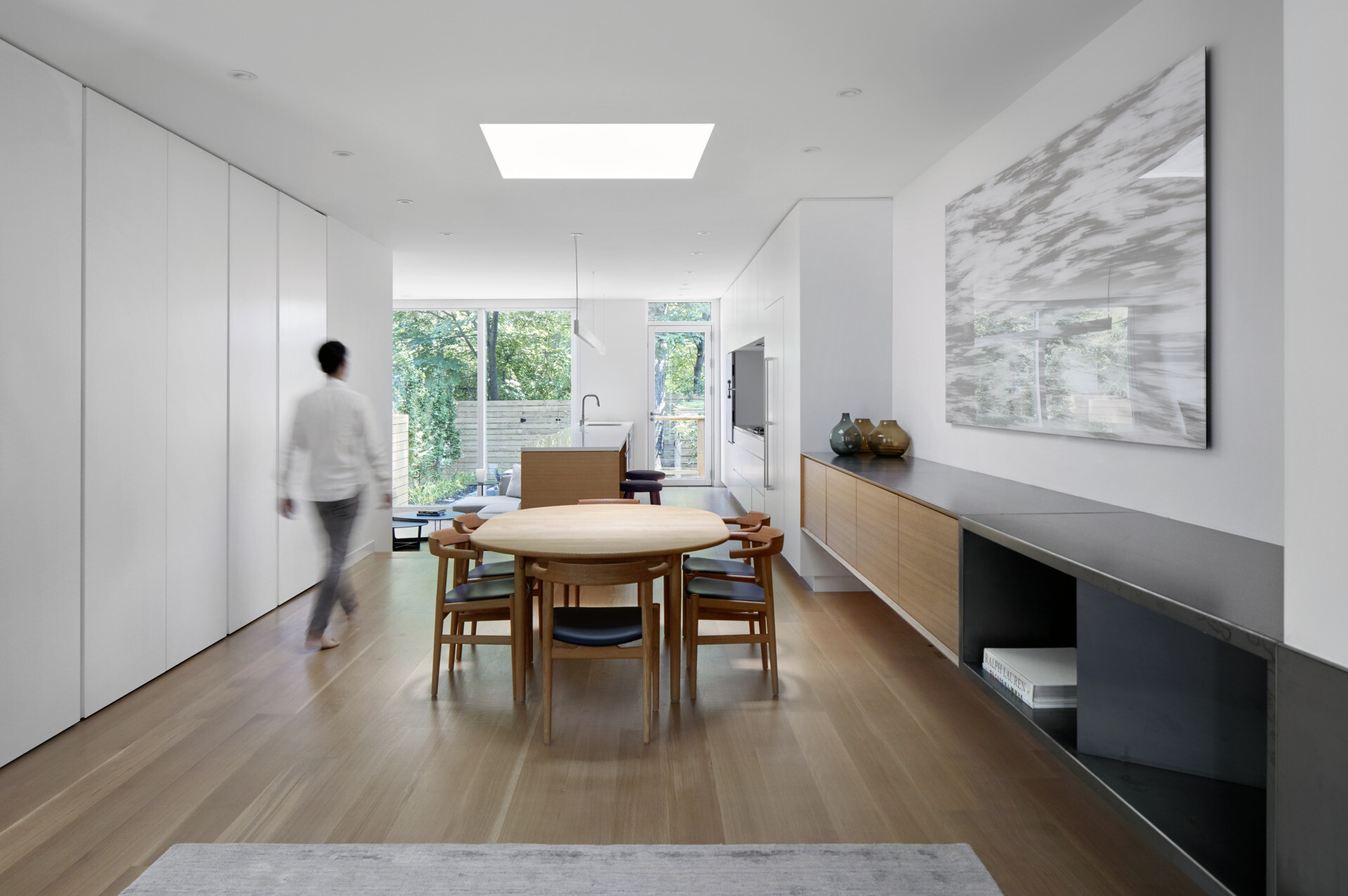 A serene dining space beneath a dramatic skylight that glows at night, blending minimal design with architectural flair.