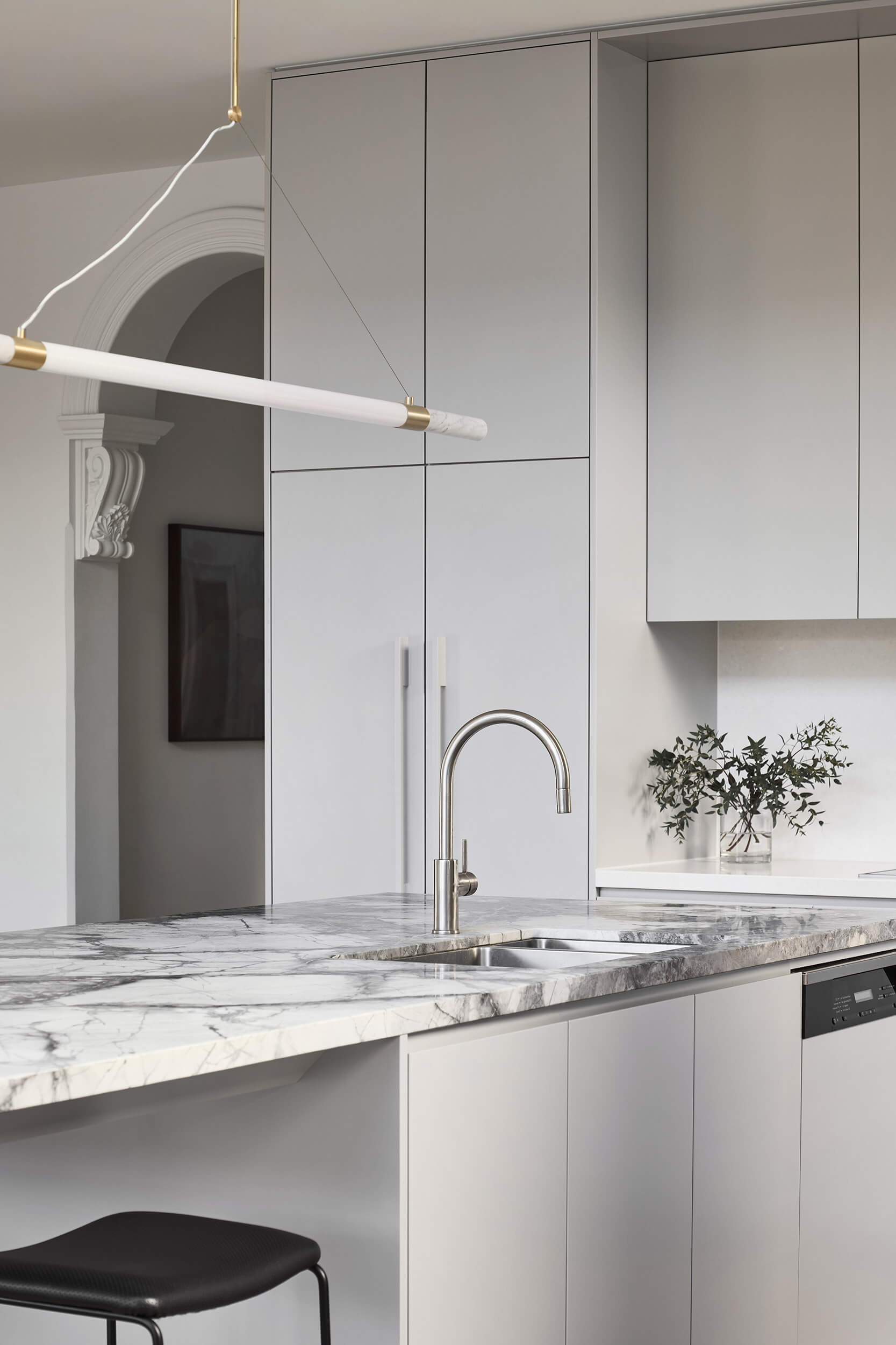This kitchen centers on a cantilevered stone island that serves as both sculptural statement and family gathering point. Suspended lighting in brass and marble continues the refined aesthetic. Hidden appliances maintain a sense of calm order, reinforcing the balance of function and beauty.