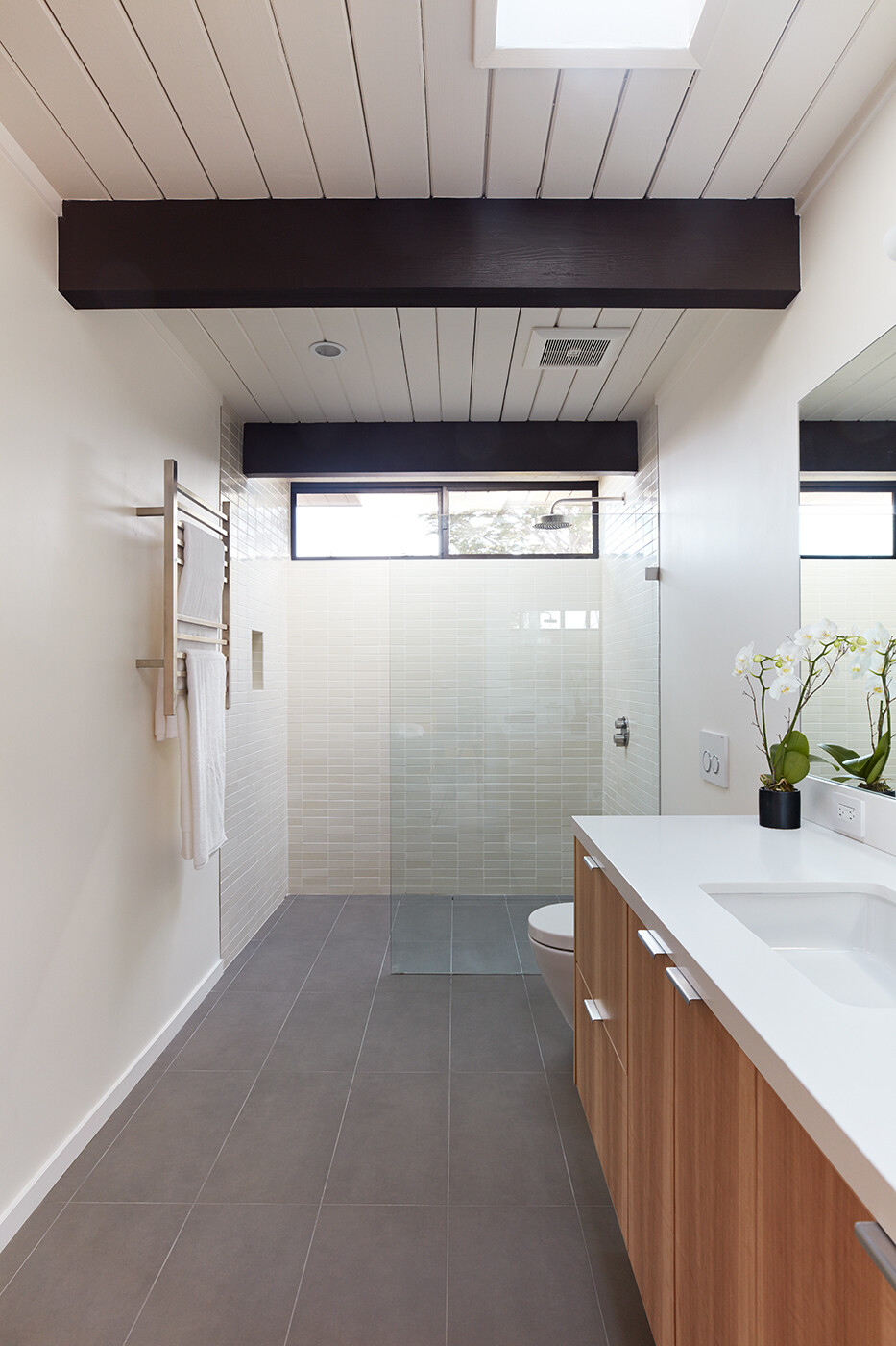 Elegant bathrooms with soft grey tones and bright finishes complete this Eichler’s understated modern look.