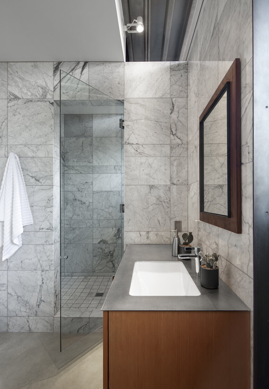 Sleek gray tiles, a matching counter, and natural wood details give the bathroom a modern, spa-like atmosphere.