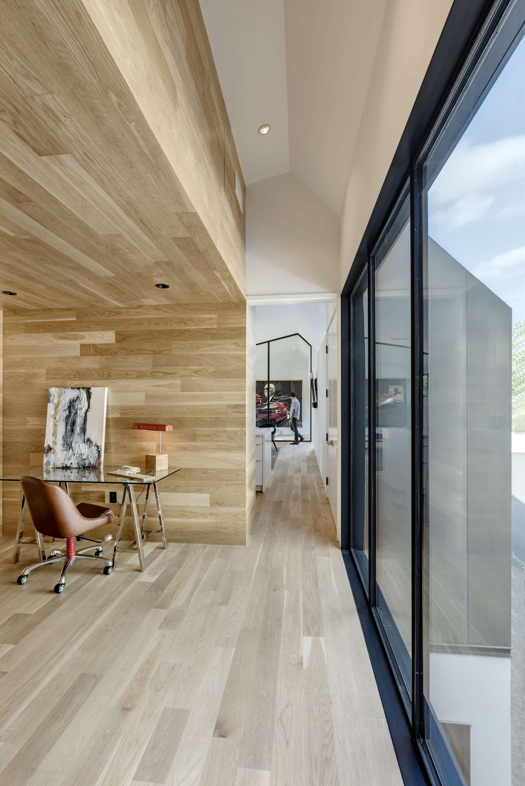 A small hallway leads to a home office nook, surrounded by natural wood for warmth and focus.