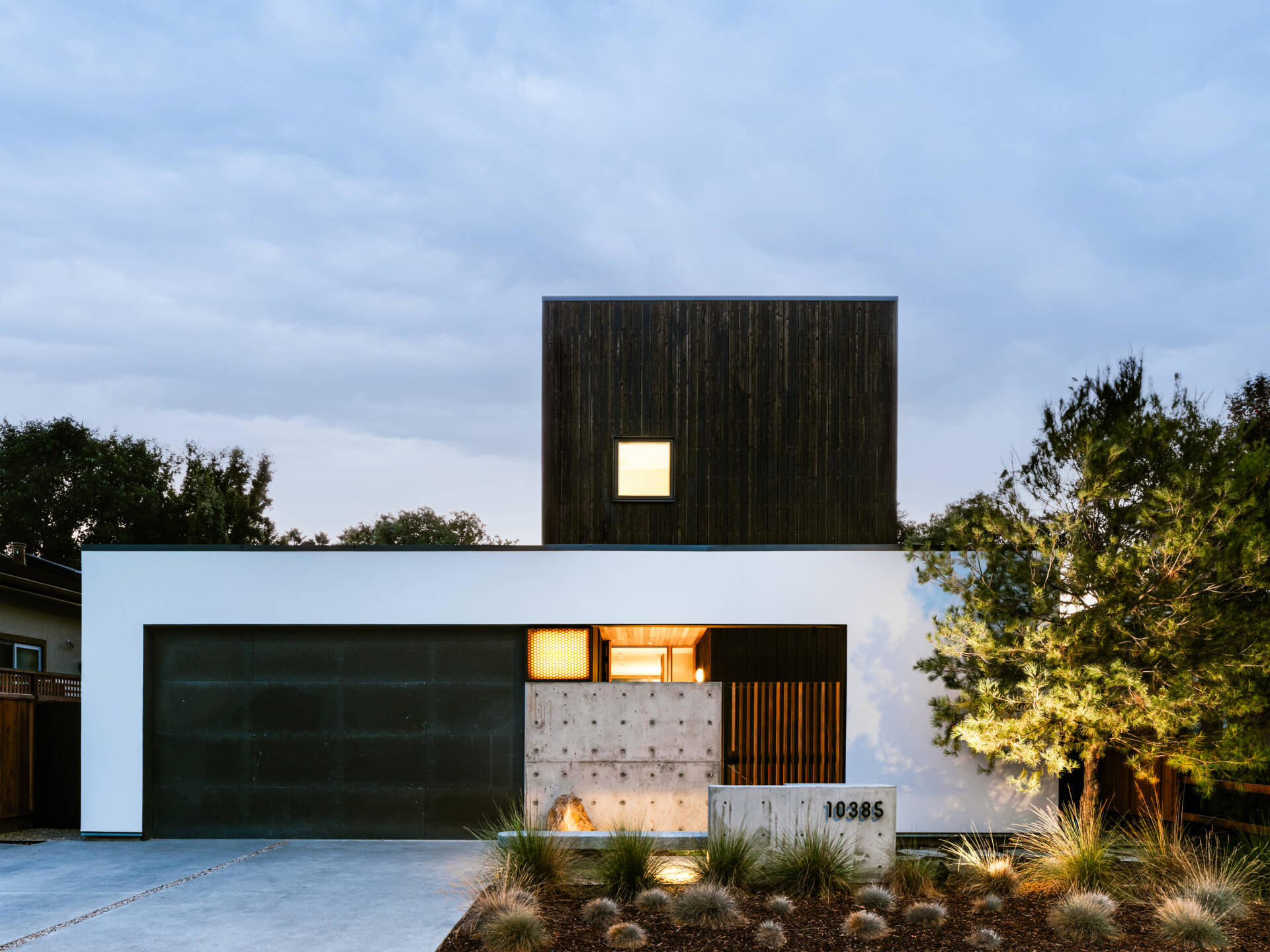 Stepped massing responds directly to strict zoning rules. From the street, white stucco walls echo surrounding houses, while the second level is clad in black shou sugi ban wood. 