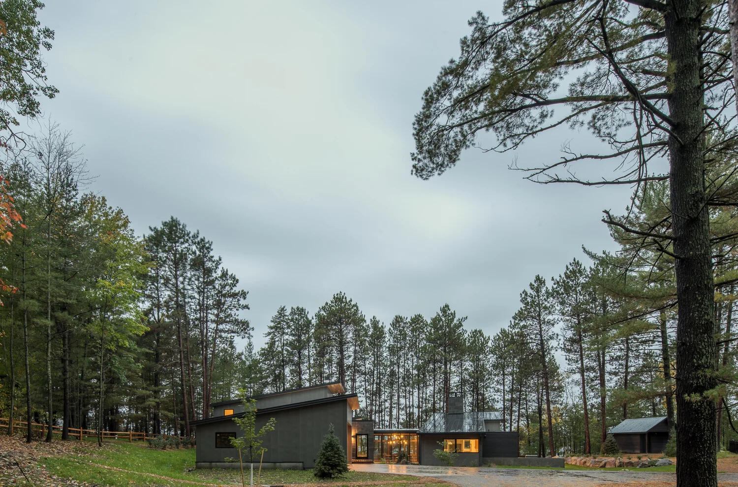This modern house has a subtle dark exterior that includes grey, black, stone and wood elements, allowing the home to blend into the forested landscape.