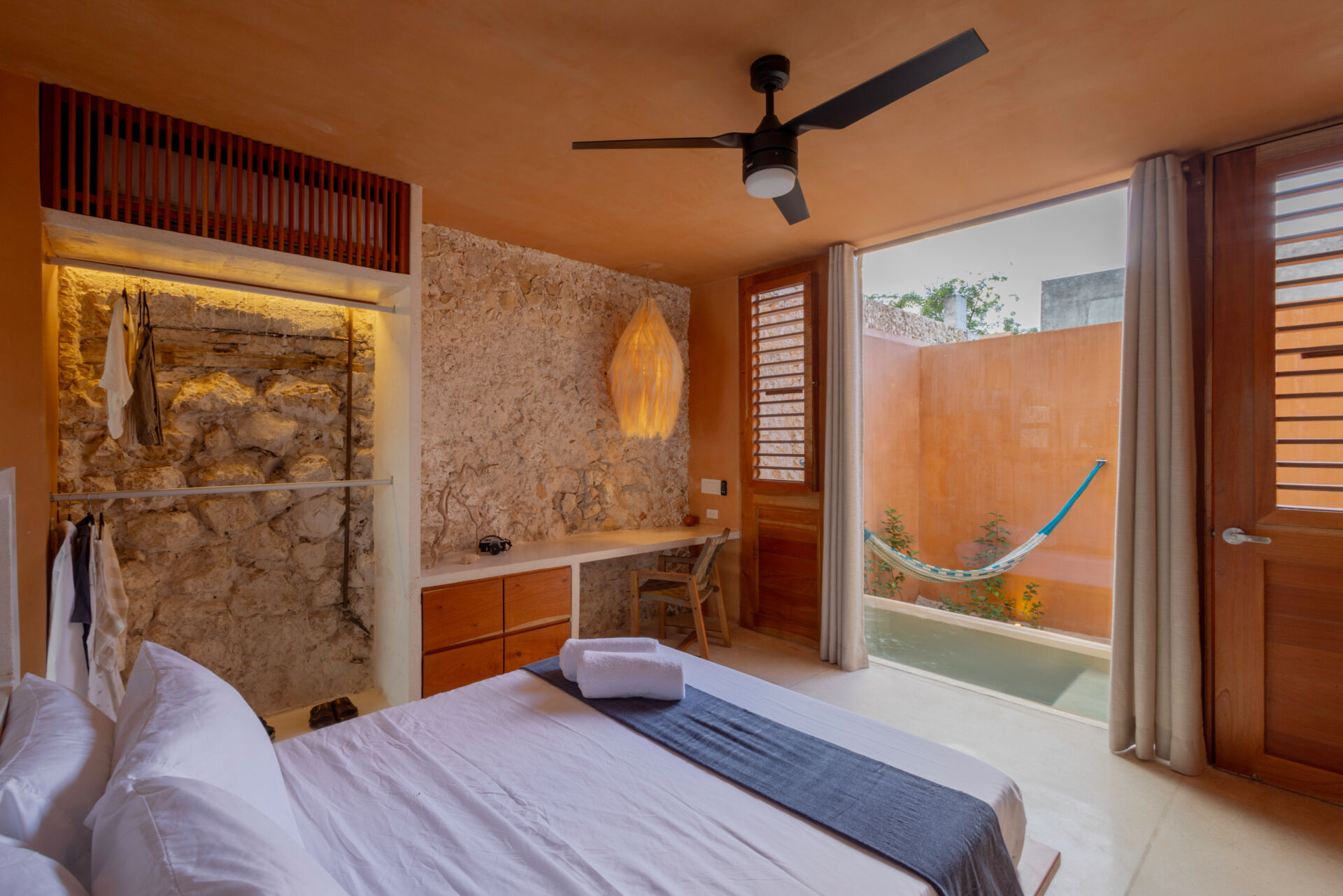 The lower unit features a garden, open kitchen, dining area, bedroom, and bathroom, designed to feel airy and connected through two sunlit courtyards.