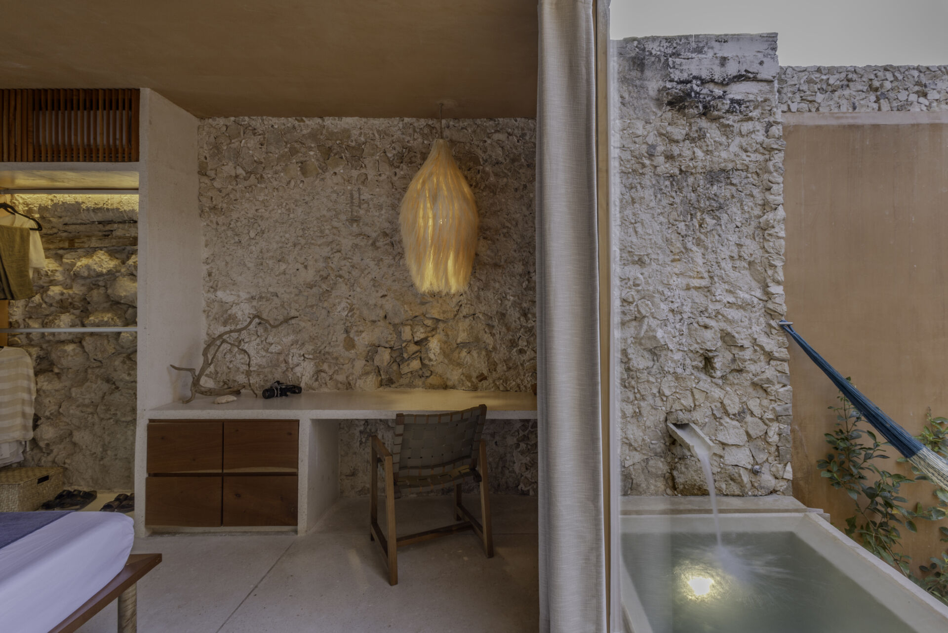 The lower unit features a garden, open kitchen, dining area, bedroom, and bathroom, designed to feel airy and connected through two sunlit courtyards.