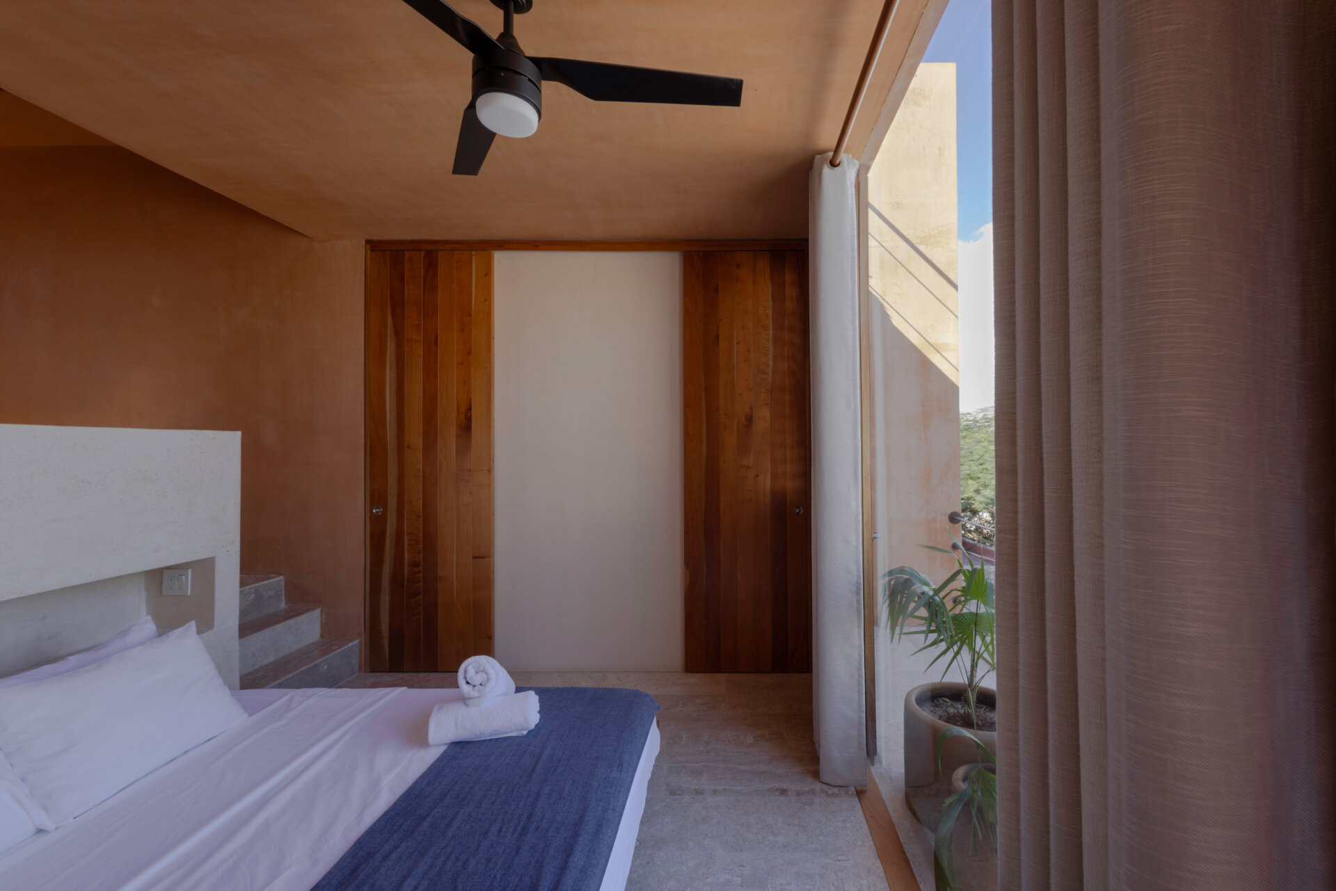 Upstairs, a large window and balcony frame the sea, with interiors designed to stay cool while capturing ocean breezes.