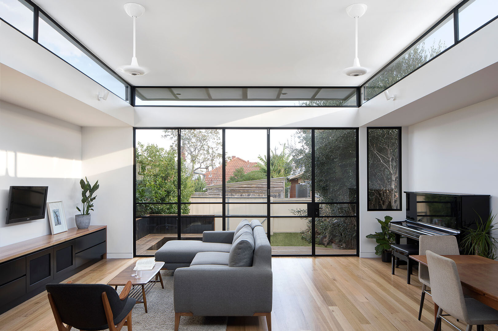 This terrace house opens to the backyard with a timber deck, built-in seating and glass doors that bring the garden directly into daily life.