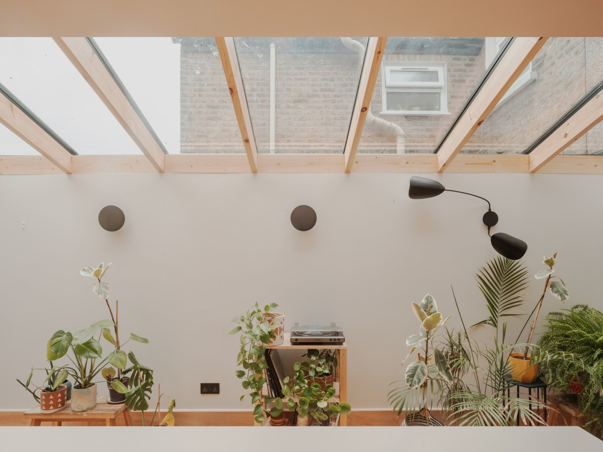 A light-filled garden extension with a new kitchen and dining area, includes pink steel, cork flooring, a pivoting door, and rooflights.
