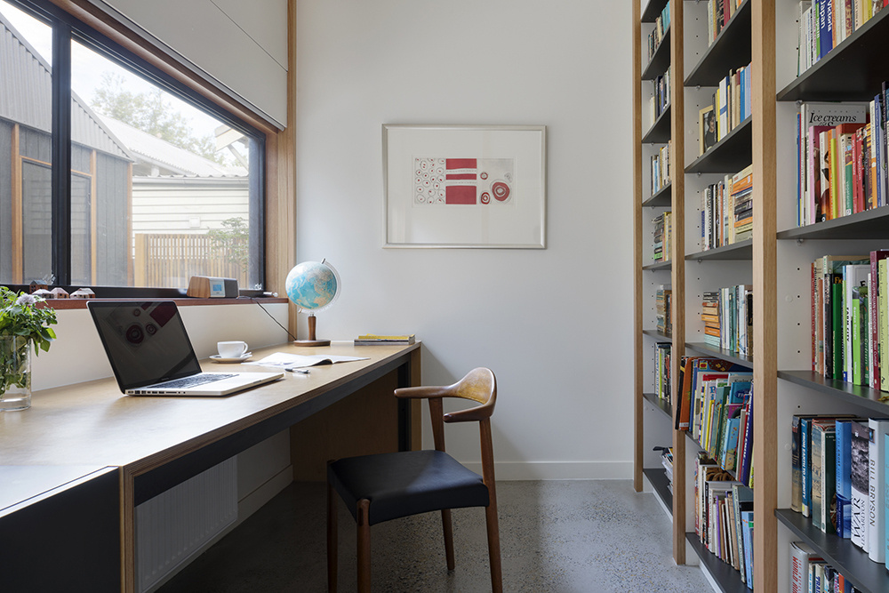 A home office with a built-in bookshelf and long desk.