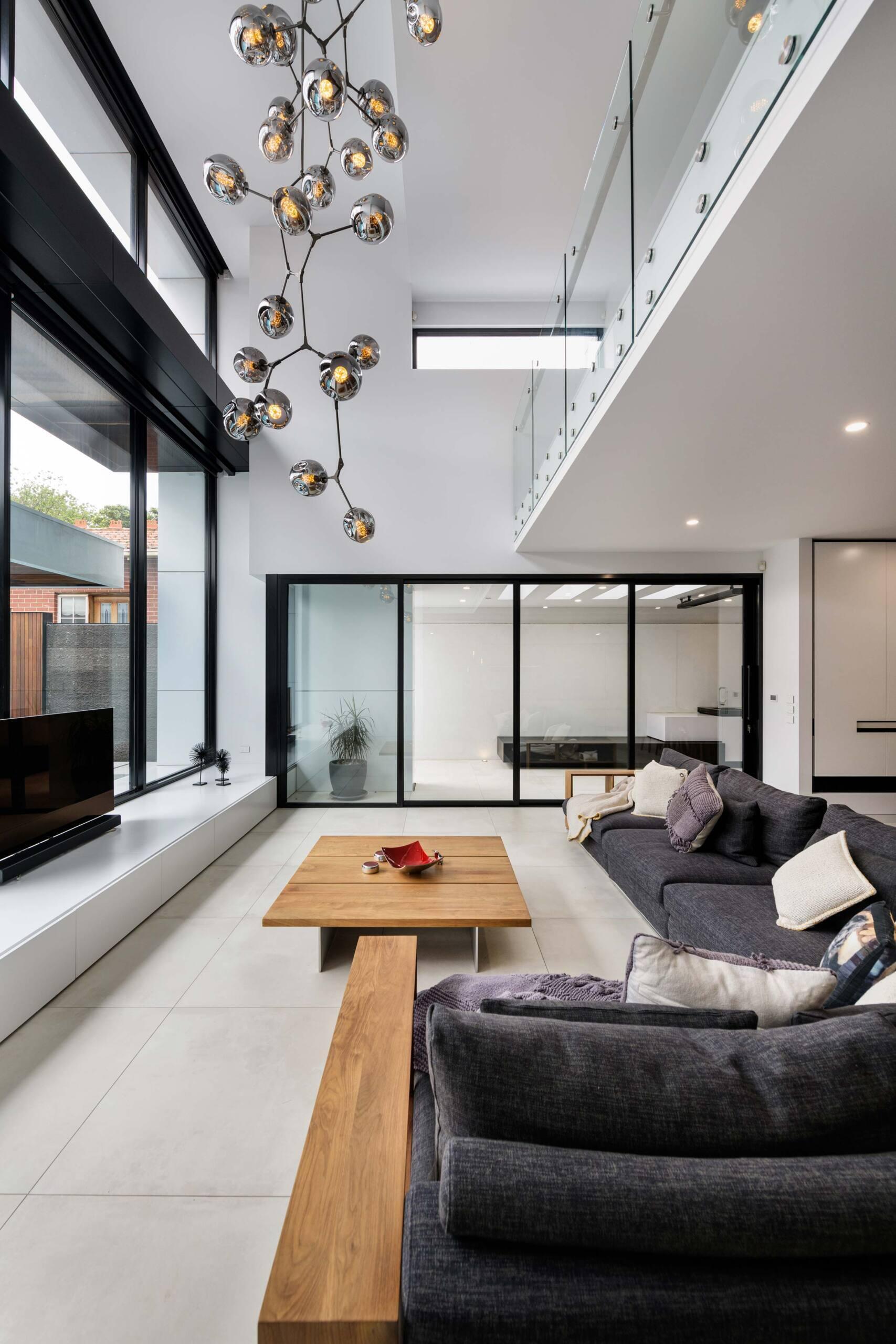 A double-height living area fills with daylight, softening the concrete and opening to the courtyard. It’s a seamless blend of volume, texture, and openness.
