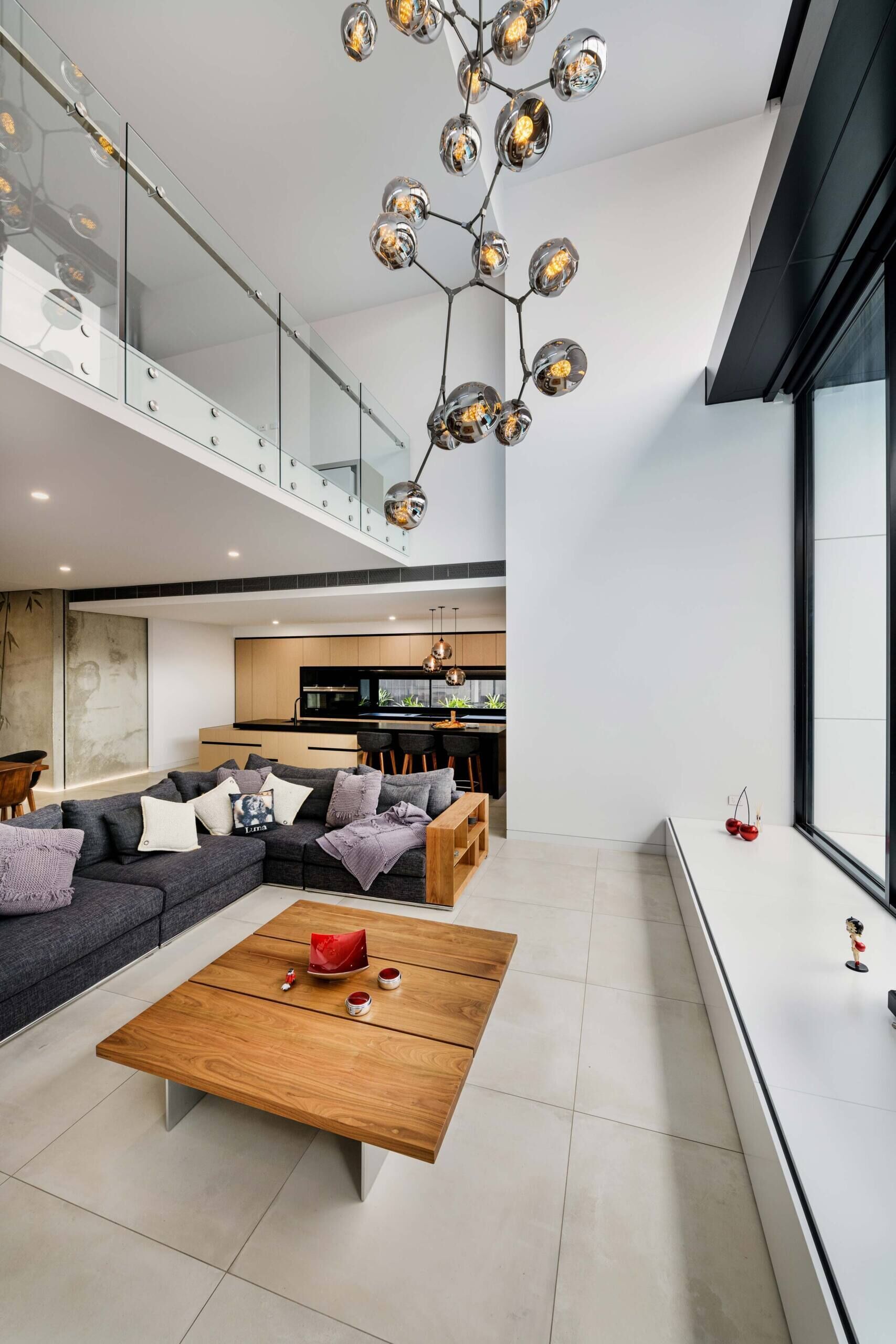 A double-height living area fills with daylight, softening the concrete and opening to the courtyard. It’s a seamless blend of volume, texture, and openness.