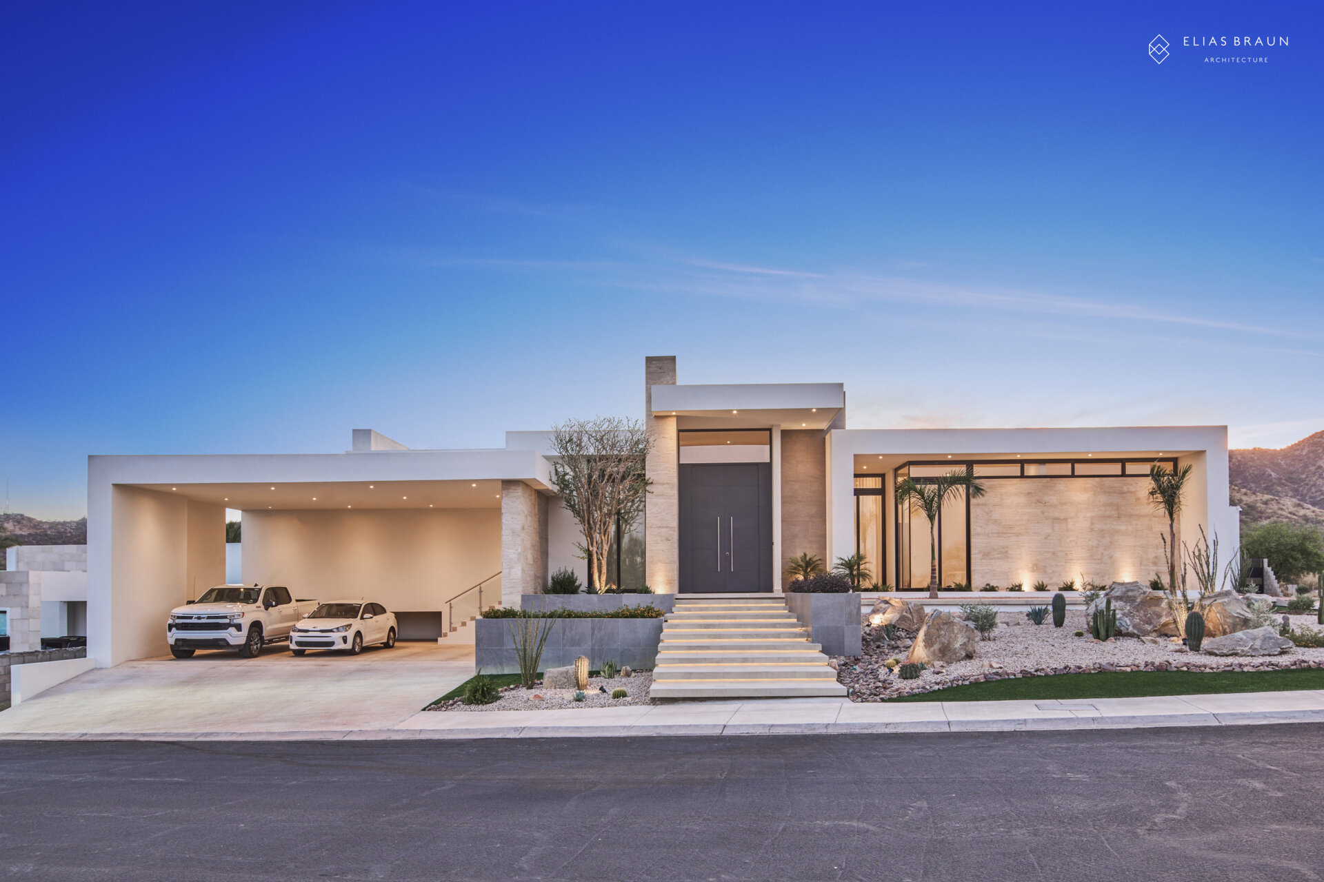 A contemporary desert home in Hermosillo, Sonora, where architecture meets precision and calm. The striking five-meter steel door opens to a light-filled interior that frames the natural reserve beyond. Every level, line, and shadow is tuned to the desert’s rhythm, creating a sense of arrival that feels both sculptural and serene.