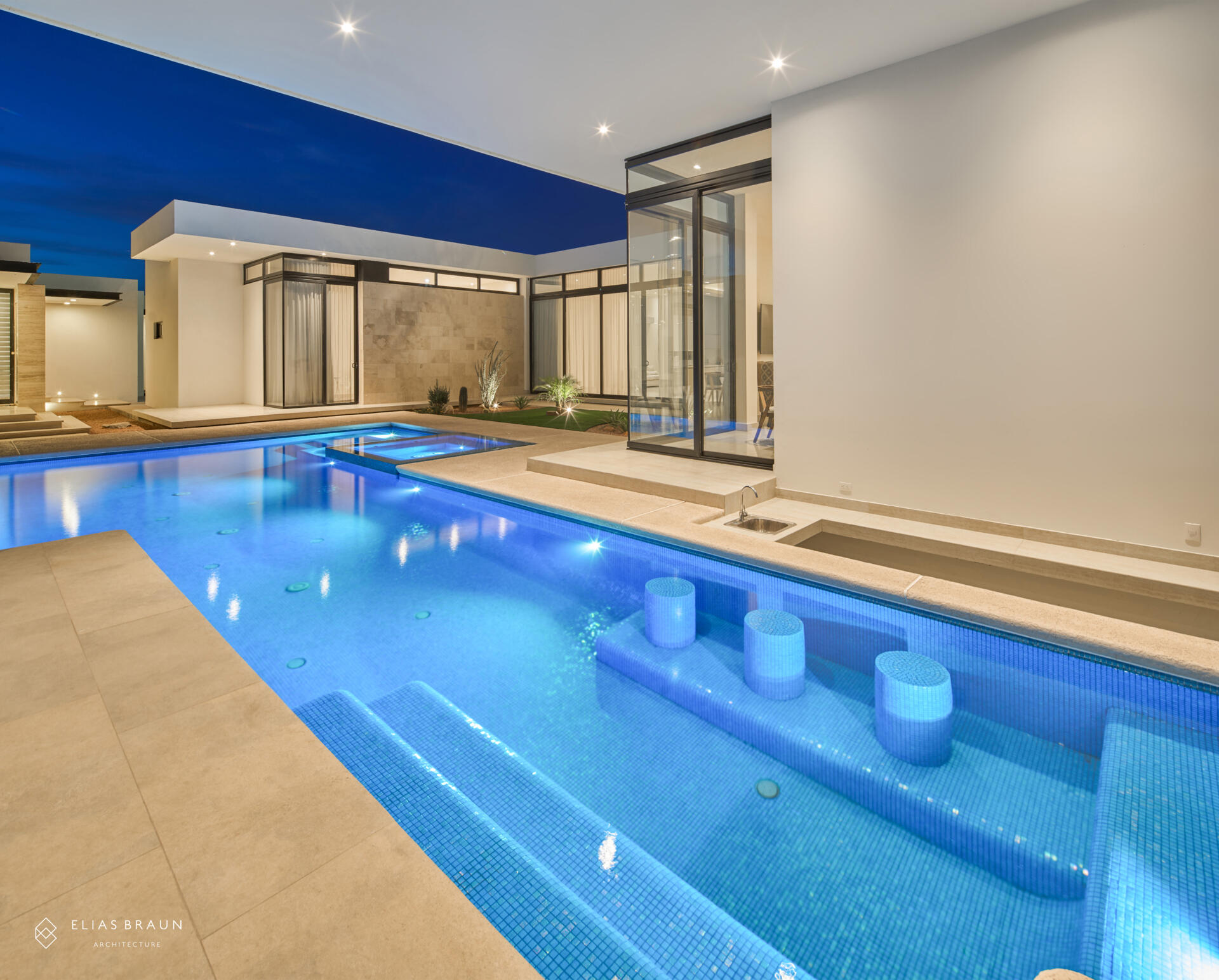 A stepped desert home where water and air define the experience. The infinity pool meets the horizon, while a central courtyard gathers breezes and connects the main house with the guest wing. Travertine terraces and soft light make every transition, from swim to social, effortless.