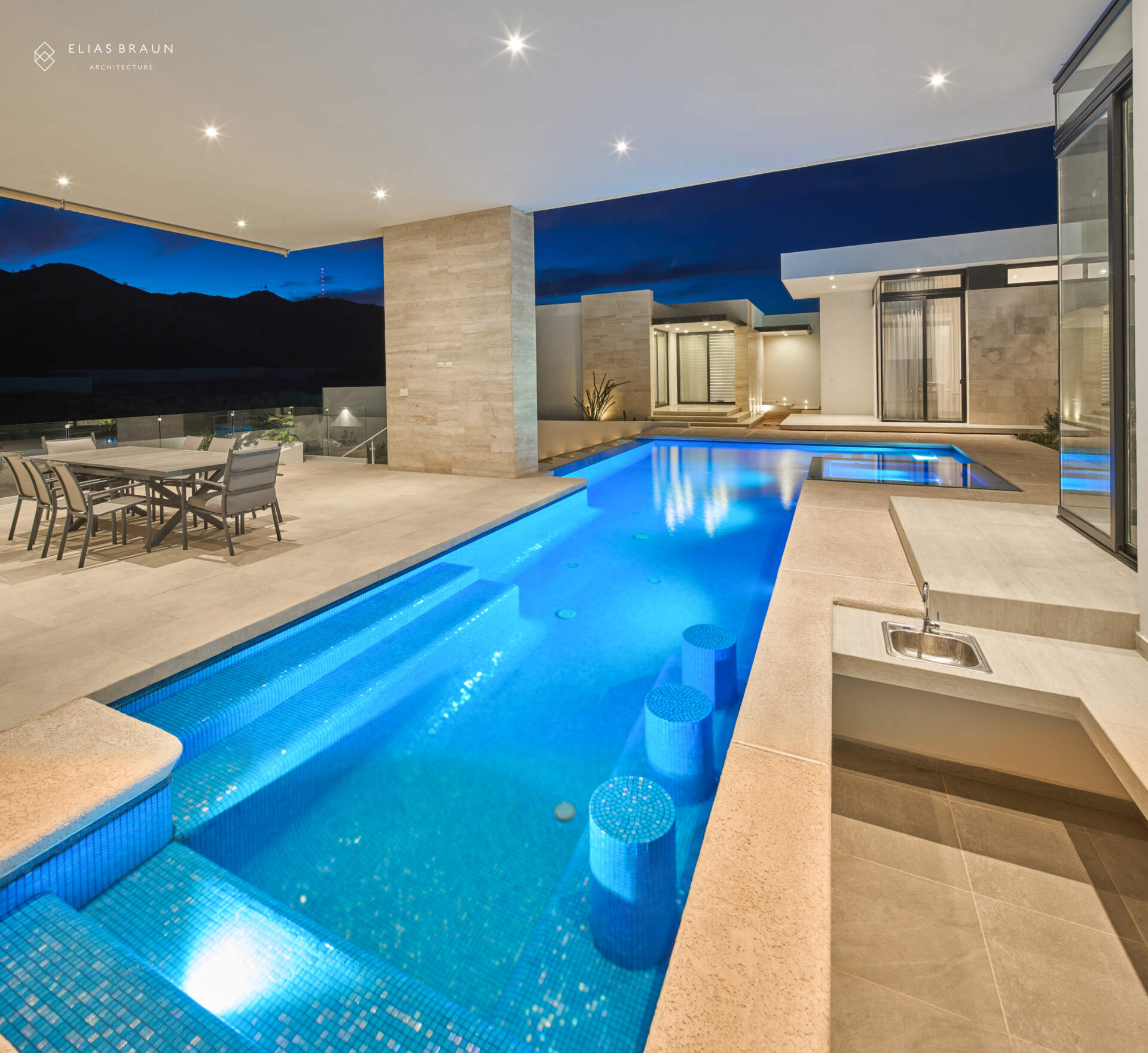 A stepped desert home where water and air define the experience. The infinity pool meets the horizon, while a central courtyard gathers breezes and connects the main house with the guest wing. Travertine terraces and soft light make every transition, from swim to social, effortless.