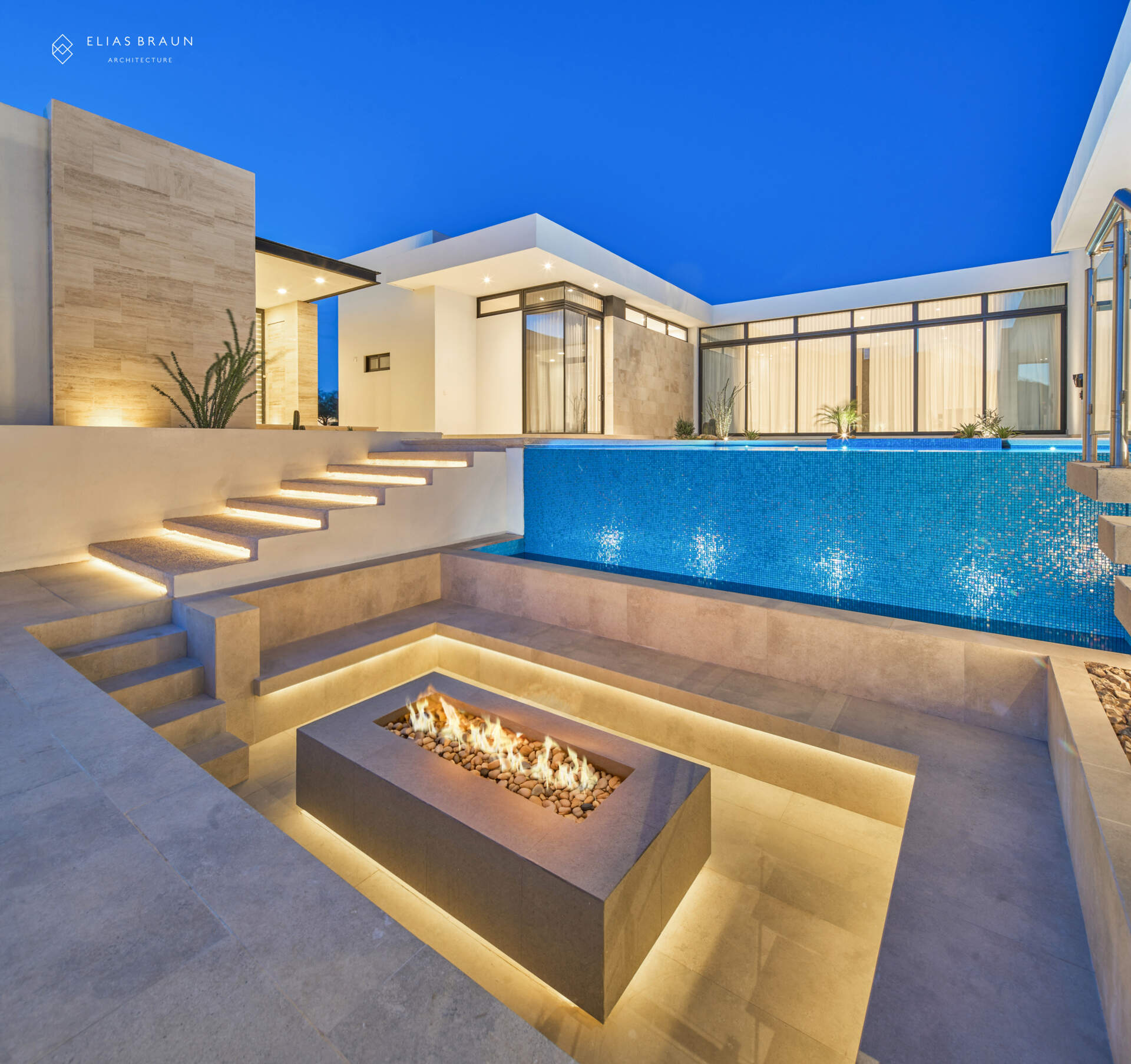 At the lowest terrace of this desert home, the fire pit becomes the gathering point when the air cools. Surrounded by travertine, glass, and desert views, it anchors evenings of quiet conversation under Sonora’s vast sky, bringing warmth to the home’s restrained, timeless palette.