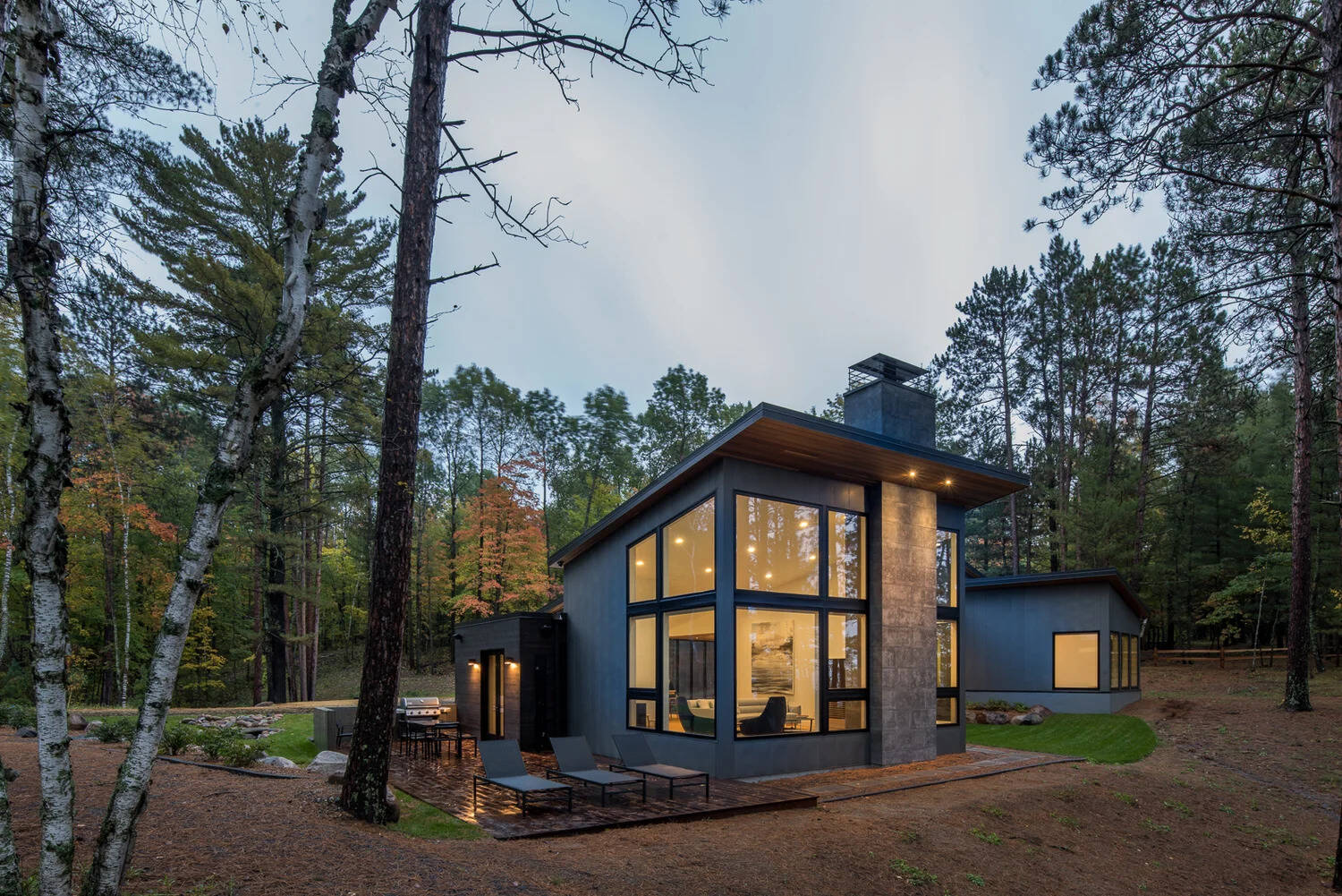 This modern house has a subtle dark exterior that includes grey, black, stone and wood elements, allowing the home to blend into the forested landscape.