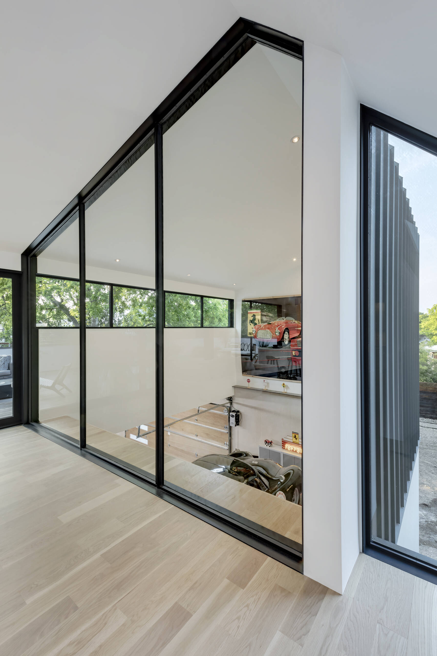 The upper level seems to float above the garage, its black-framed glass wall providing a view of the cars below. The architects used this visual connection to blur the boundary between hobby and home, a perfect reflection of the couple’s intertwined lifestyle.