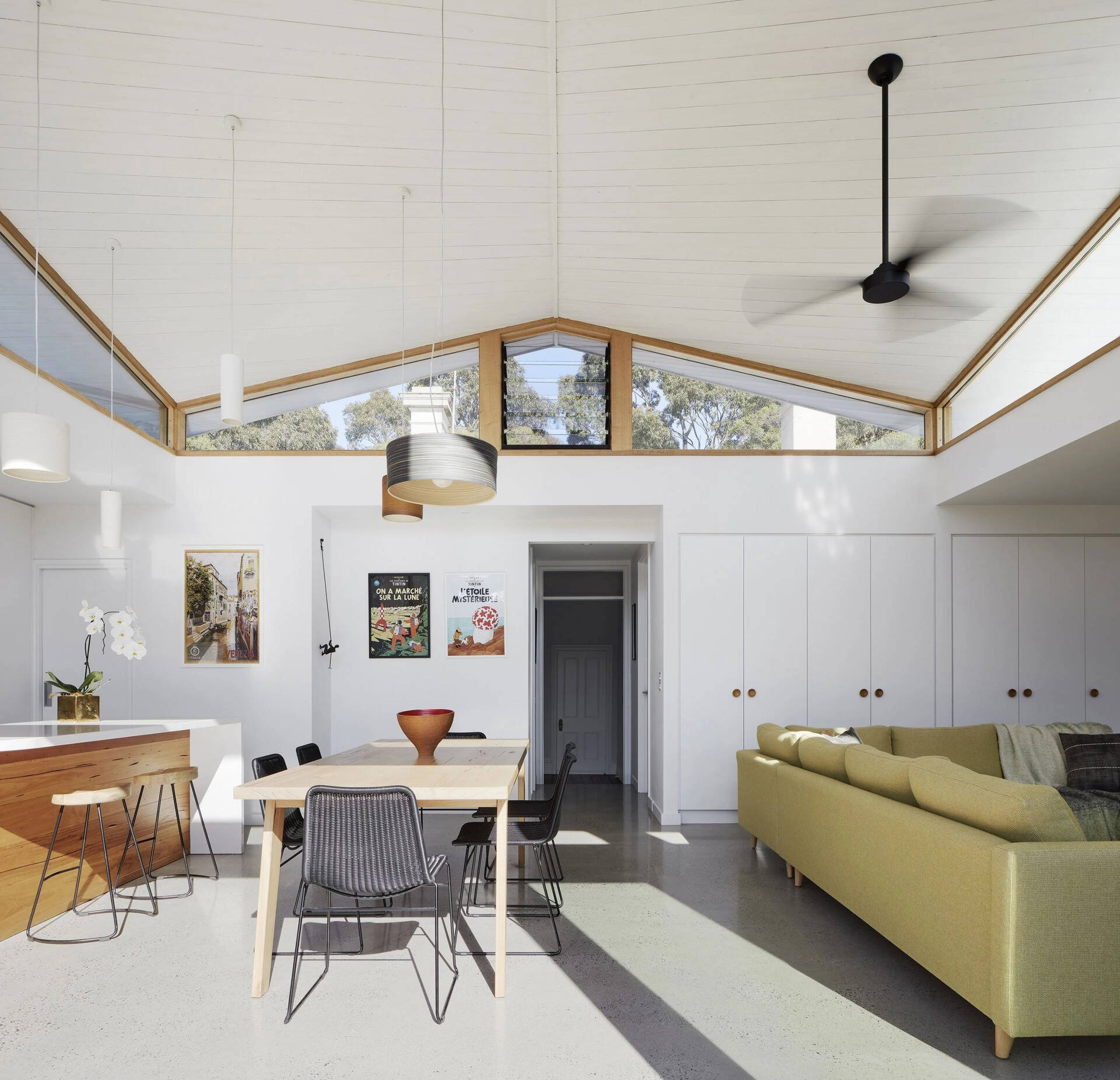 Clerestory windows follow the roofline, flooding the interior with natural light. A white timber ceiling brings a sense of airiness and light to the interior, emphasizing the sculptural curves of the roof above.