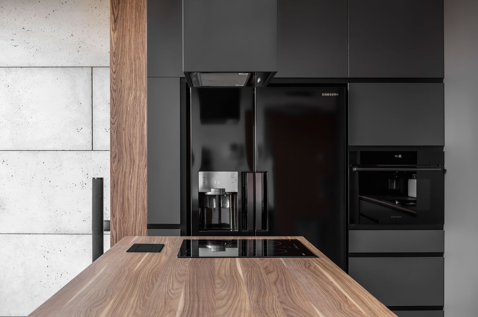 In this kitchen, dark grey walls and cabinets are softened by warm wood details. Glossy black appliances add a sleek, modern edge that complements the apartment’s masculine aesthetic. The minimalist palette continues through every surface, proving that simplicity can be expressive.