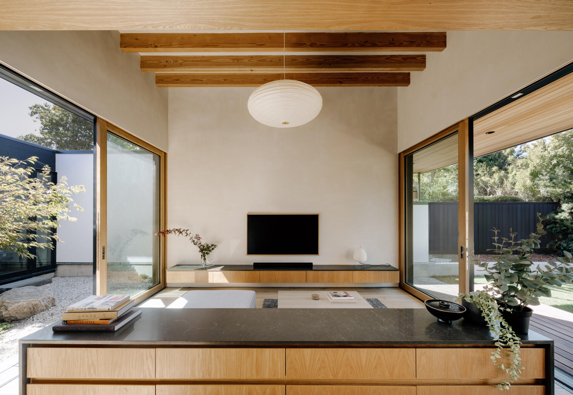 Natural clay plaster walls and warm wood tones create a welcoming hub. Floor-to-ceiling doors open to the courtyards, bringing sunlight, greenery, and fresh air deep into the living areas. The space encourages informal gatherings while maintaining a serene connection to the outdoors.