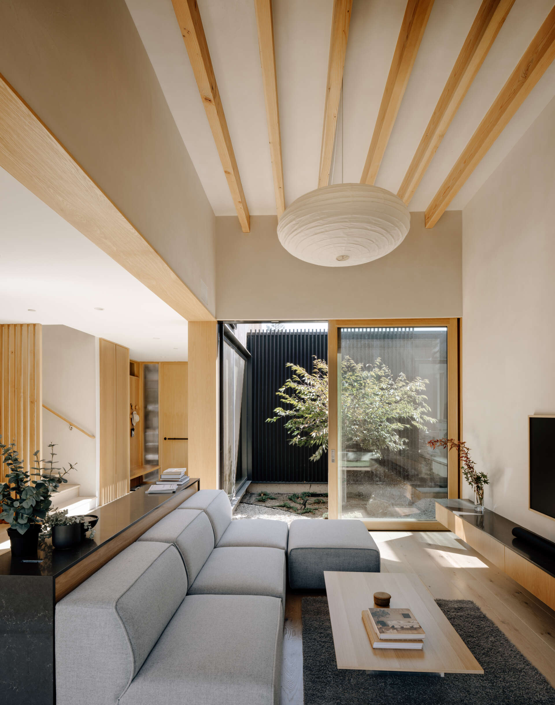 Natural clay plaster walls and warm wood tones create a welcoming hub. Floor-to-ceiling doors open to the courtyards, bringing sunlight, greenery, and fresh air deep into the living areas. The space encourages informal gatherings while maintaining a serene connection to the outdoors.