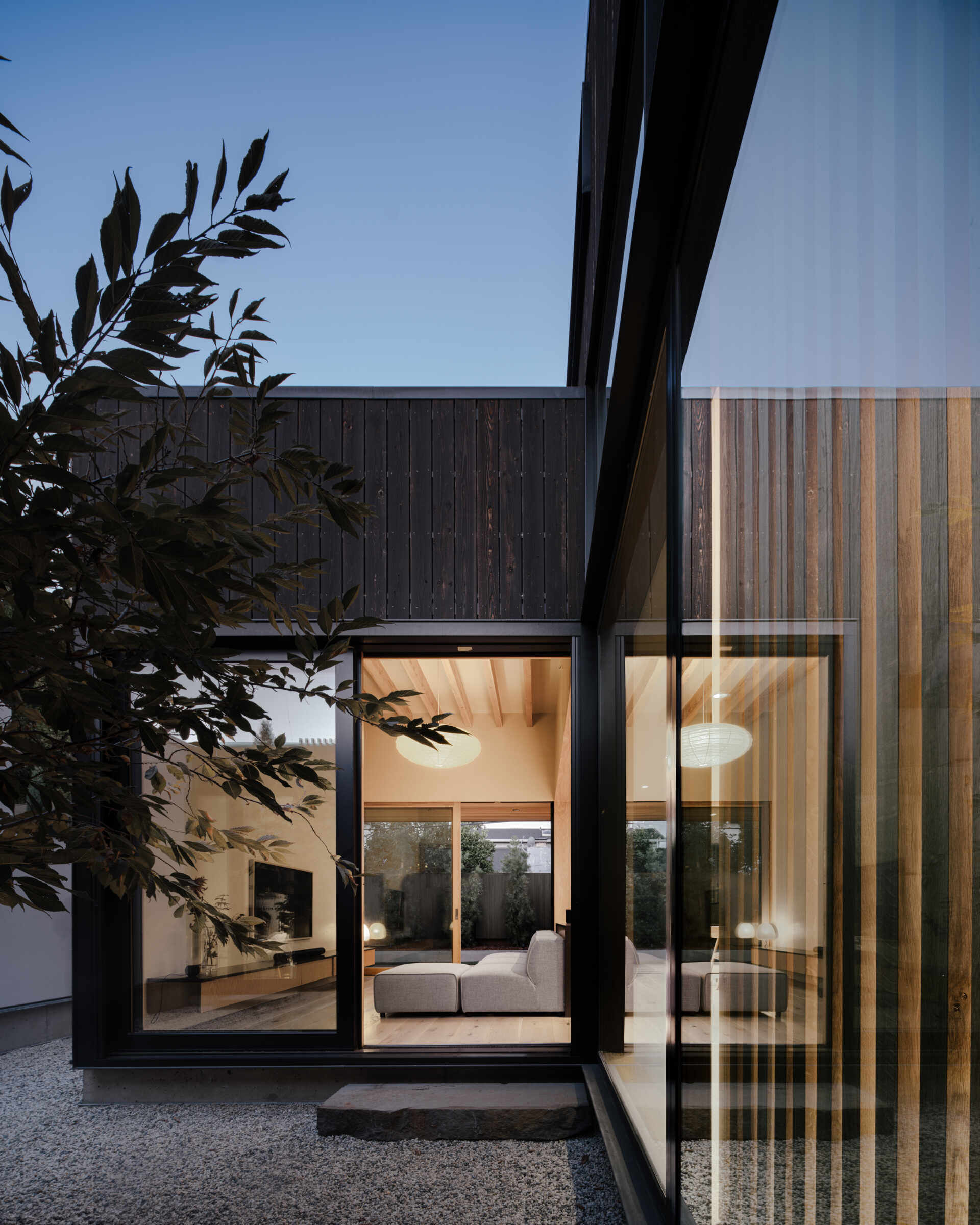 Natural clay plaster walls and warm wood tones create a welcoming hub. Floor-to-ceiling doors open to the courtyards, bringing sunlight, greenery, and fresh air deep into the living areas. The space encourages informal gatherings while maintaining a serene connection to the outdoors.