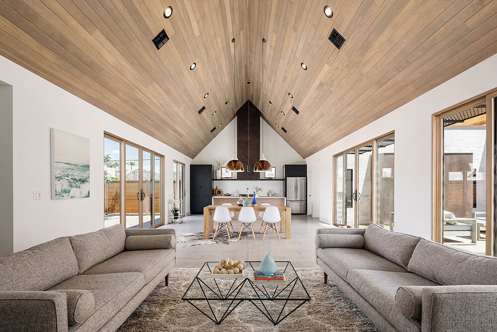 The vaulted hemlock ceiling and white walls create a warm, open space that connects indoor and outdoor living through light-filled courtyards.