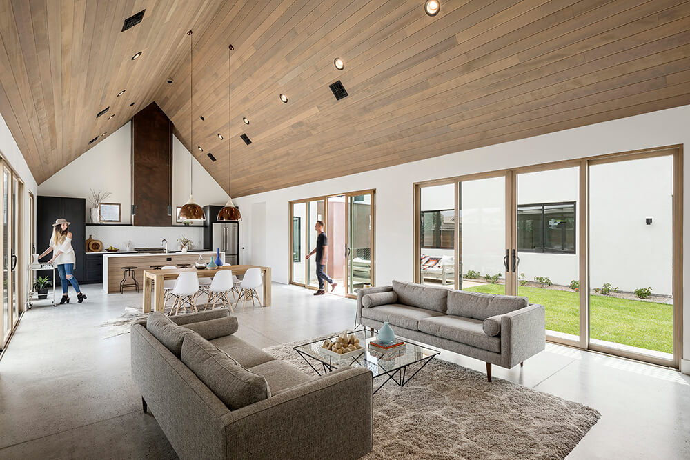 The vaulted hemlock ceiling and white walls create a warm, open space that connects indoor and outdoor living through light-filled courtyards.