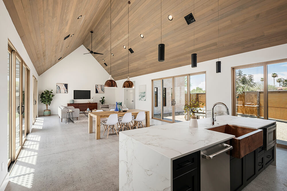The vaulted hemlock ceiling and white walls create a warm, open space that connects indoor and outdoor living through light-filled courtyards.