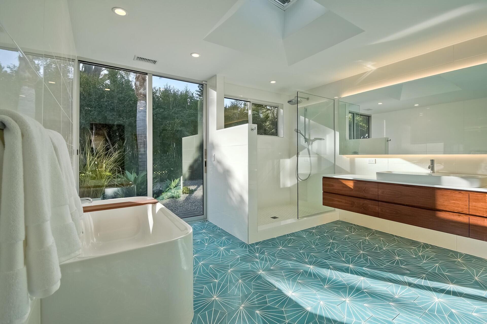 Thisi mid-century modern inspired bathroom surprises with a burst of color on the tiled floor. Against a mostly white backdrop, it becomes an energizing detail in an otherwise serene space.