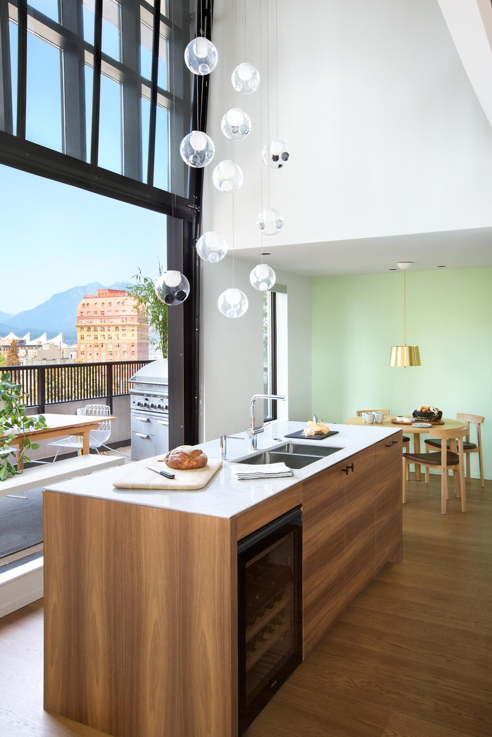 Wood runs quietly through the entire apartment, grounding the modern surfaces with warmth. The kitchen island and lower cabinetry are wrapped in walnut, their tone deep enough to feel rich but still light enough to catch the natural glow from the windows.