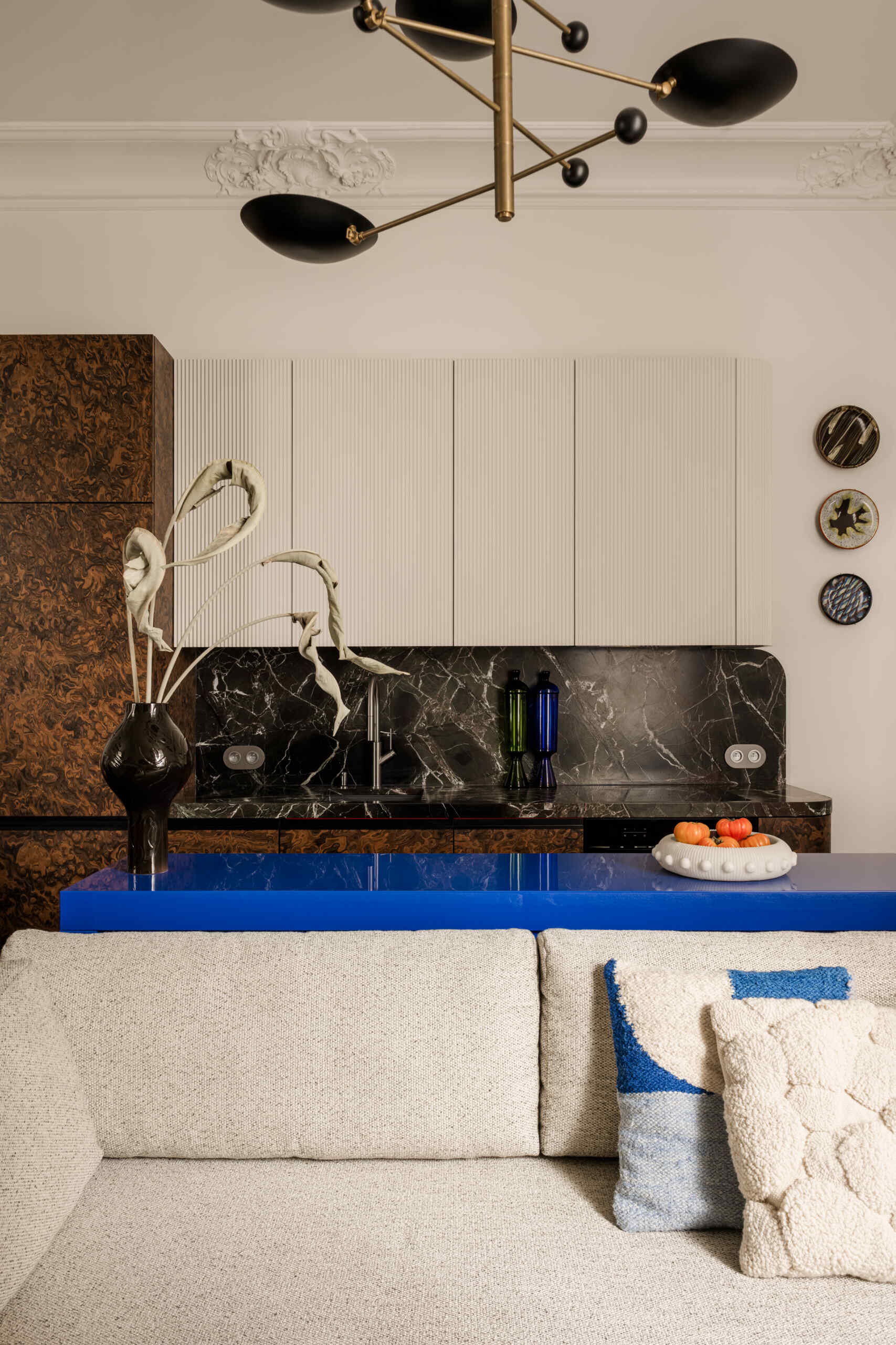In the kitchen, a deep green Rosso Levanto marble meets California Burl veneer for a dramatic contrast. A burst of Chinese red inside the cabinets adds surprise, while a glossy ultramarine console defines the open-plan living area with bold color and precision.