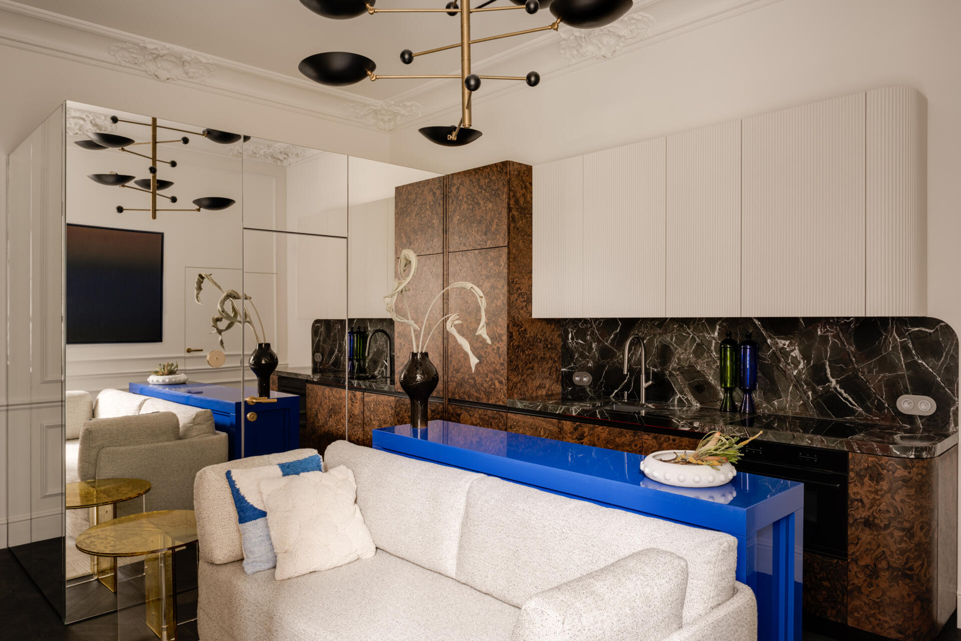 In the kitchen, a deep green Rosso Levanto marble meets California Burl veneer for a dramatic contrast. A burst of Chinese red inside the cabinets adds surprise, while a glossy ultramarine console defines the open-plan living area with bold color and precision.