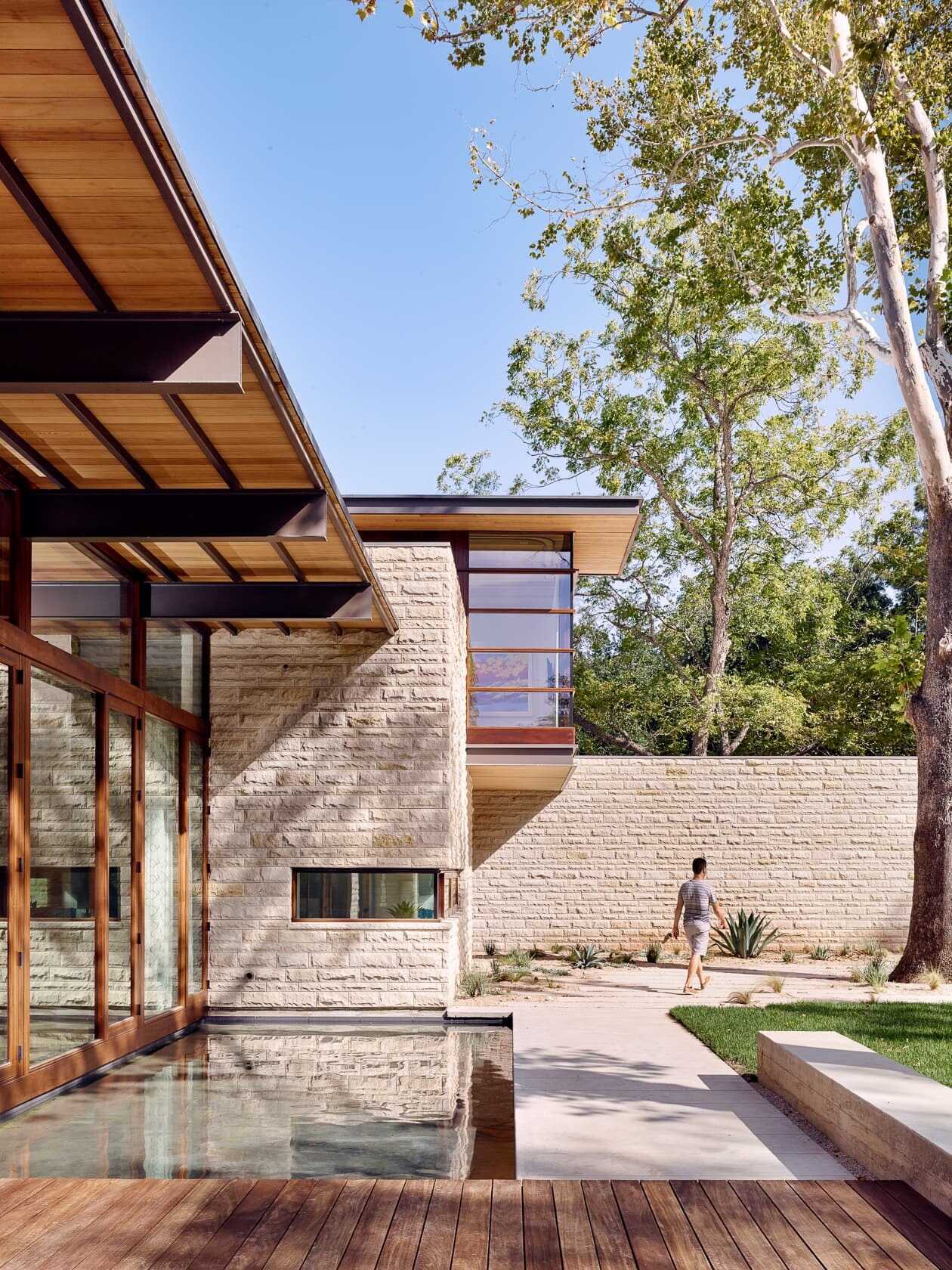 A covered deck and shimmering pool extend toward the lake, merging shade, sunlight, and water in one perfect outdoor retreat.