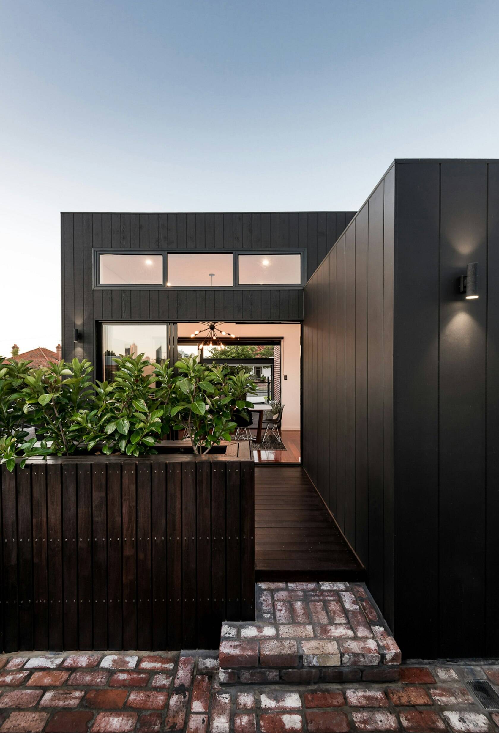 Th contemporary home's outdoor area blends comfort and design, with built-in seating, planters, and a cozy firepit perfect for entertaining.
