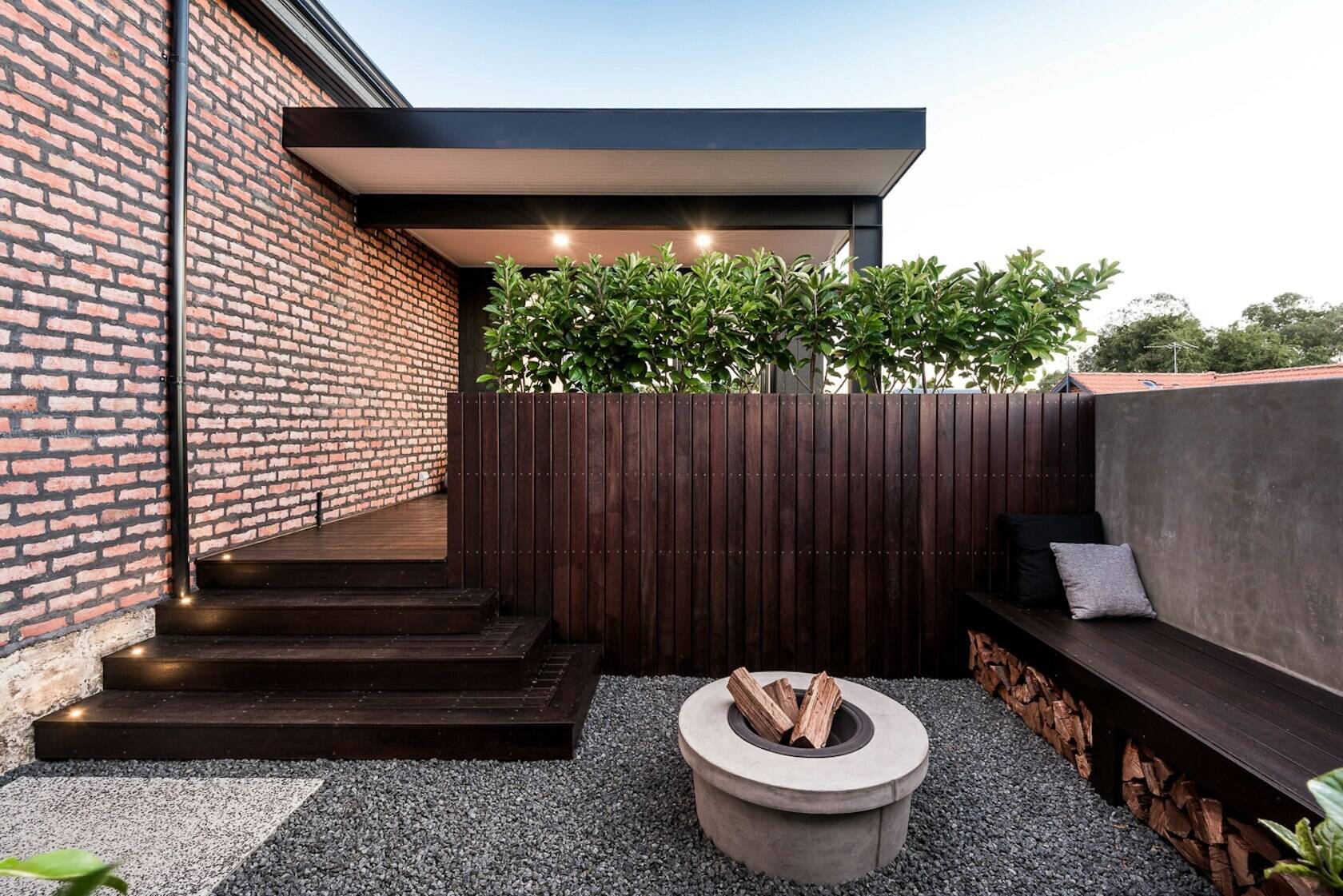 Th contemporary home's outdoor area blends comfort and design, with built-in seating, planters, and a cozy firepit perfect for entertaining.