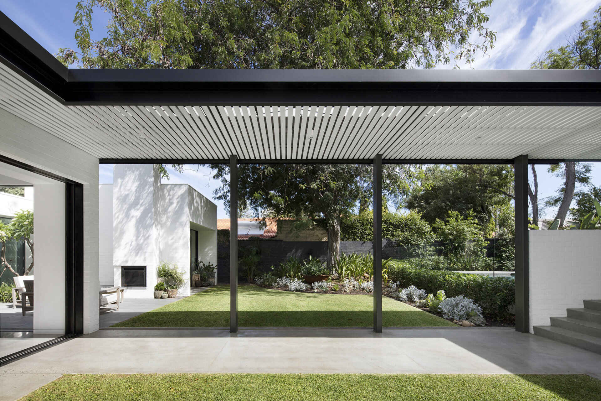Small grassy lawn beneath a tree offers a tranquil space to unwind beside the pool.