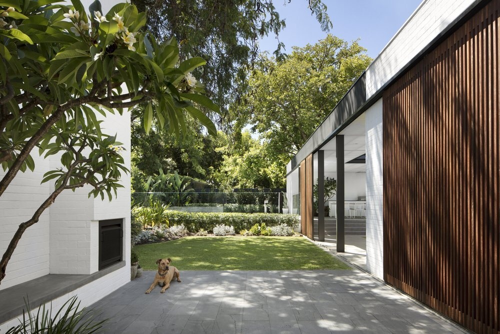 Small grassy lawn beneath a tree offers a tranquil space to unwind beside the pool.