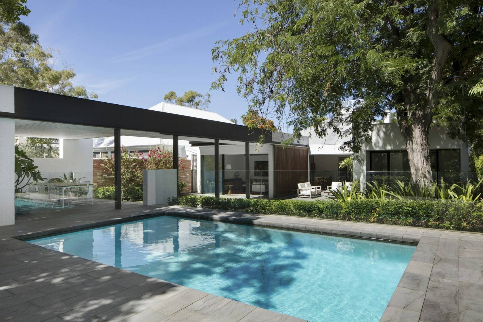 A glass-fenced swimming pool reflecting the clean geometry of the home’s modern extension.