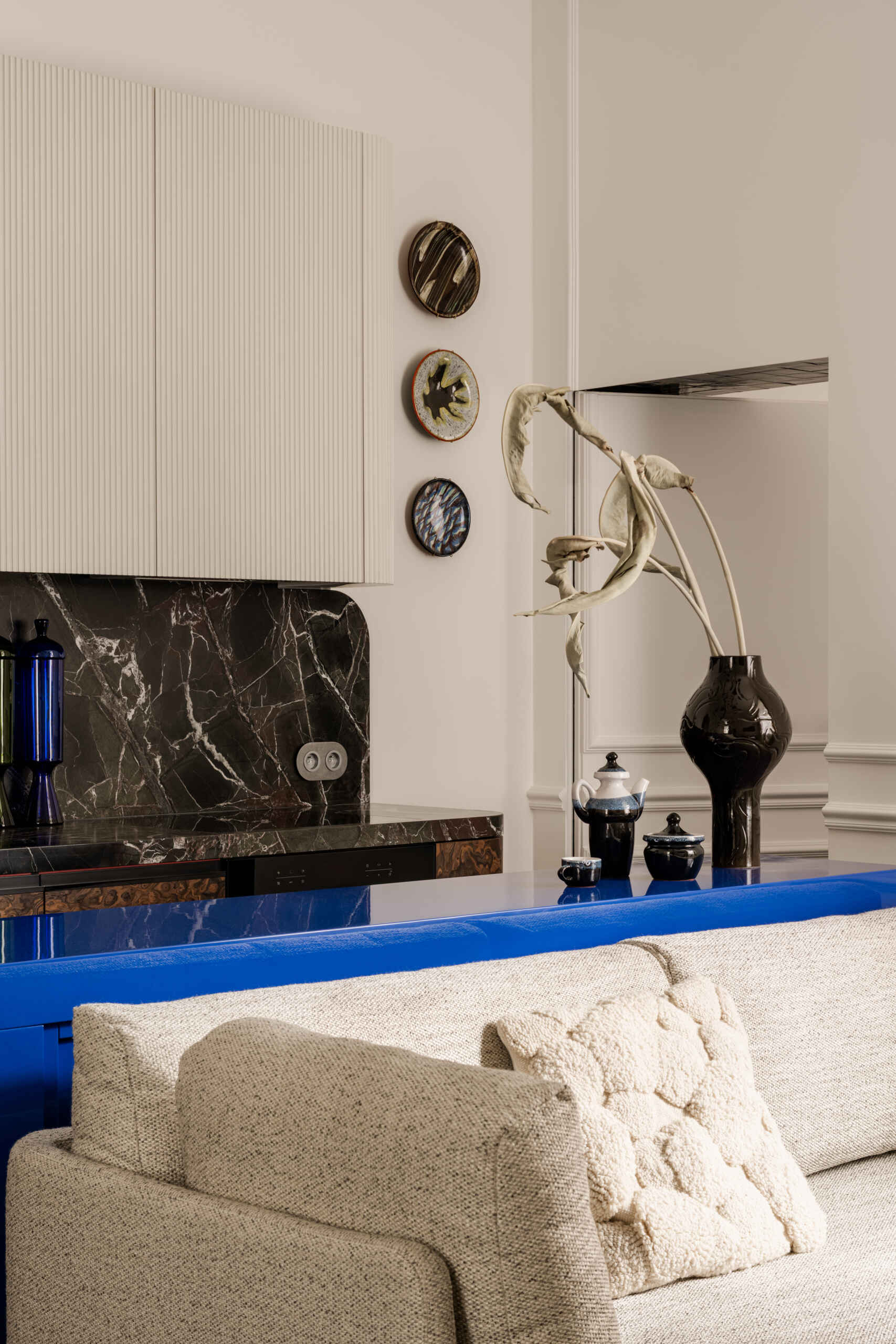 A concealed door melts into the wall mouldings, leading to the bedroom through a tiled threshold that glimmers like a secret passage. It’s a clever, poetic moment that turns a small transition into pure design theatre.