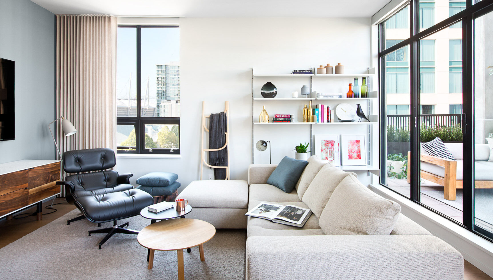 Instead of exposed brick and rough finishes, the living room in this loft relies on black-framed windows, crisp white surfaces, and clean architectural lines to suggest structure and discipline.
The contrast of cool materials with gentle light sets the tone. There’s a sense of order and balance, steel and glass meet wood and daylight. It’s industrial design that feels lived-in, not hard-edged.
