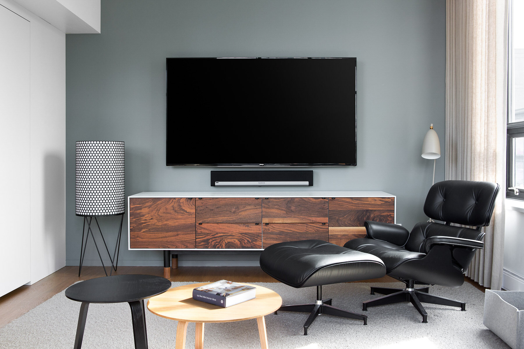 A modern living room with a matte gray accent wall, wood console, and black accents.