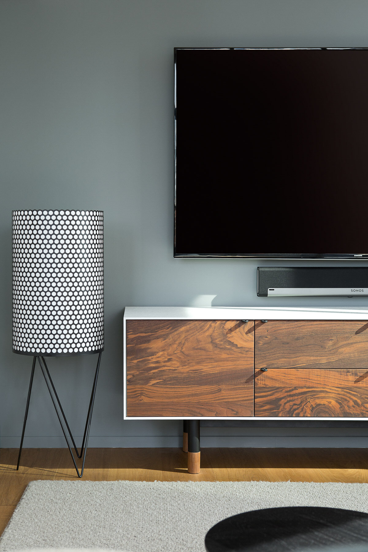 A modern living room with a matte gray accent wall, wood console, and black accents.