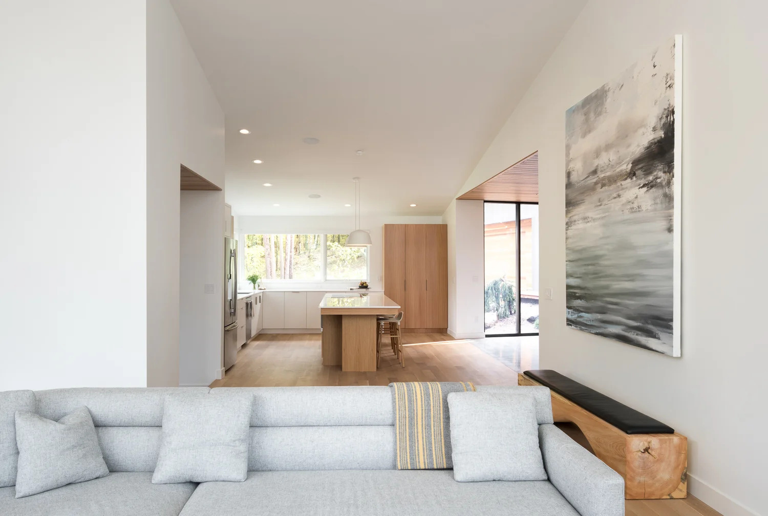 Just off the kitchen is the main living room. Large windows that wrap around the room show off the tree views, while a fireplace creates a focal point in the room.