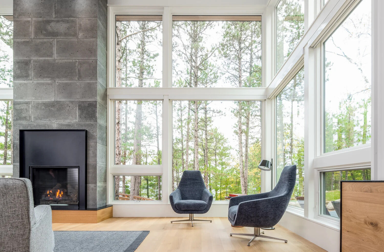Just off the kitchen is the main living room. Large windows that wrap around the room show off the tree views, while a fireplace creates a focal point in the room.