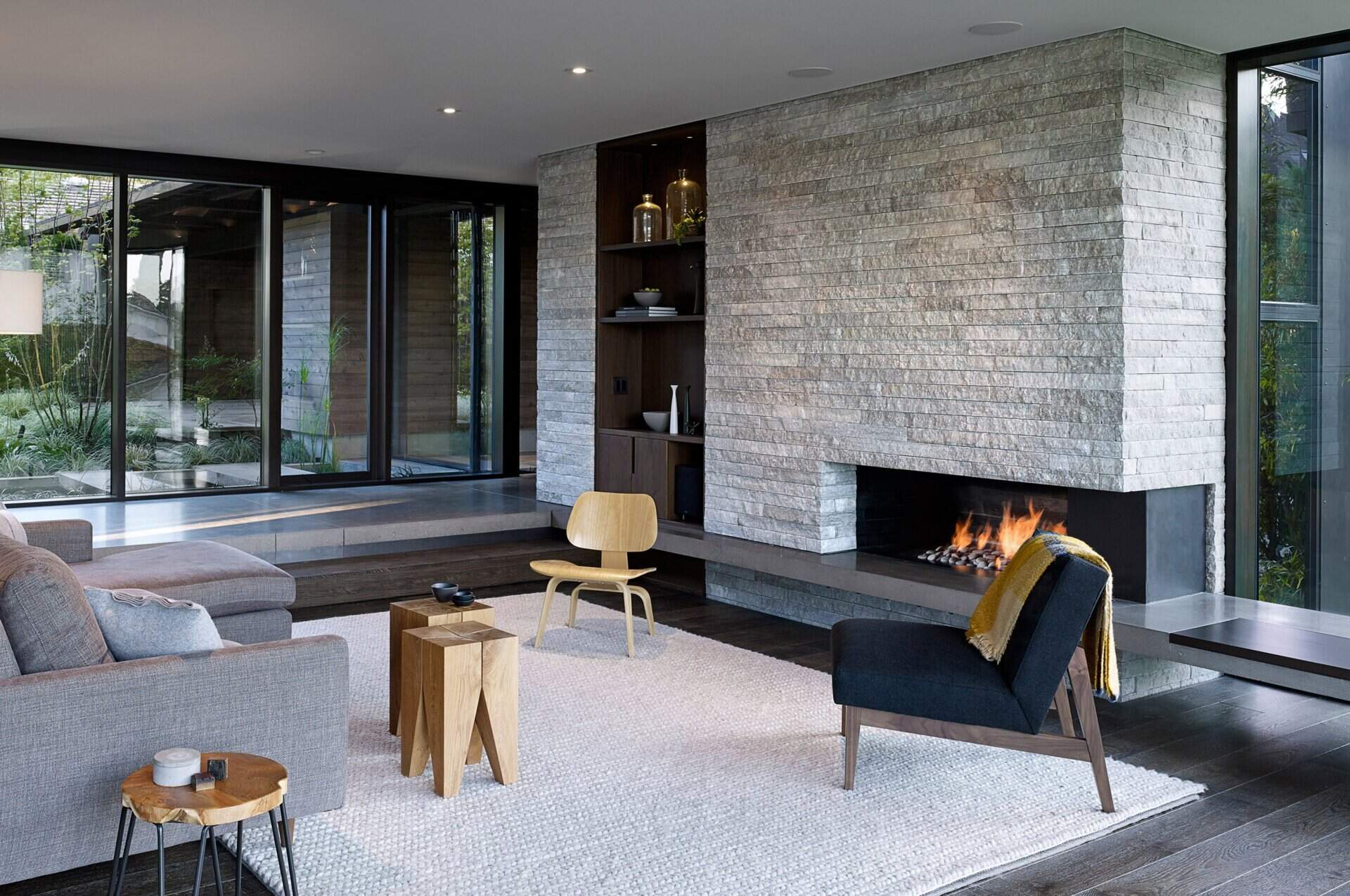 A stone accent wall, built-in bookcase, and sweeping windows transform the once-dark living room into a bright and welcoming gathering space.