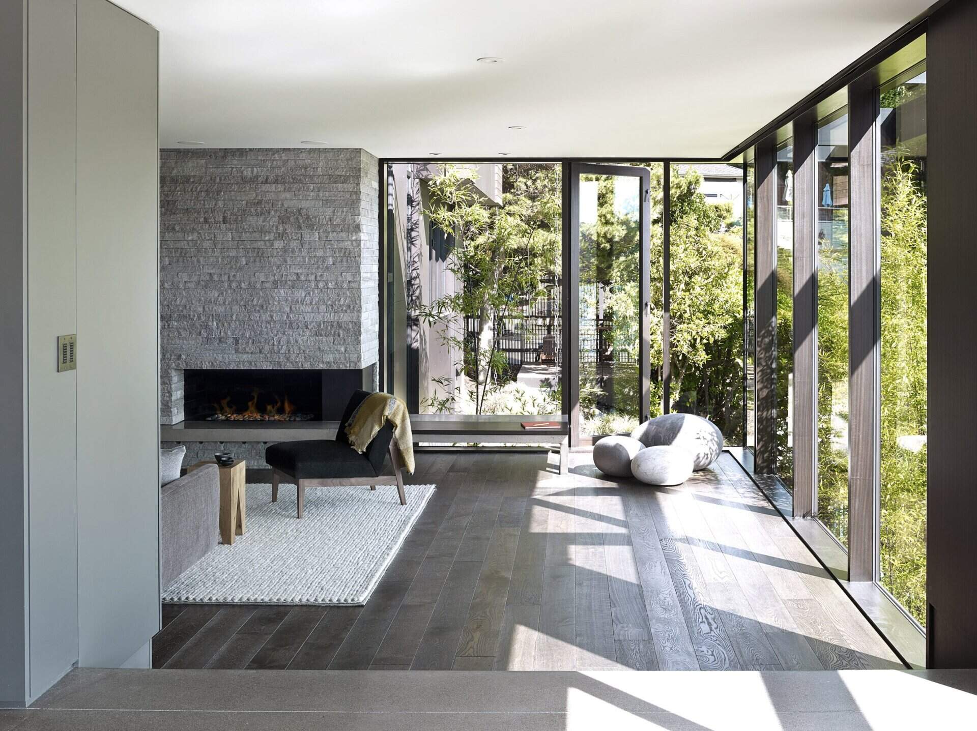 A stone accent wall, built-in bookcase, and sweeping windows transform the once-dark living room into a bright and welcoming gathering space.